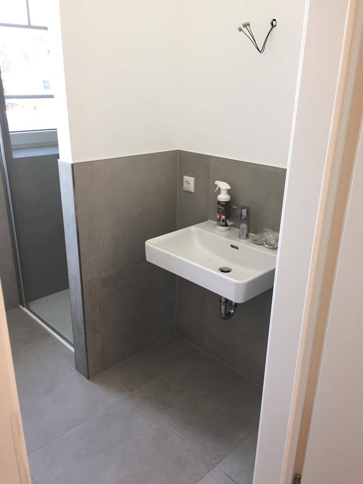 Modernes Badezimmer mit schwebendem Waschbecken und grauen Wandfliesen.