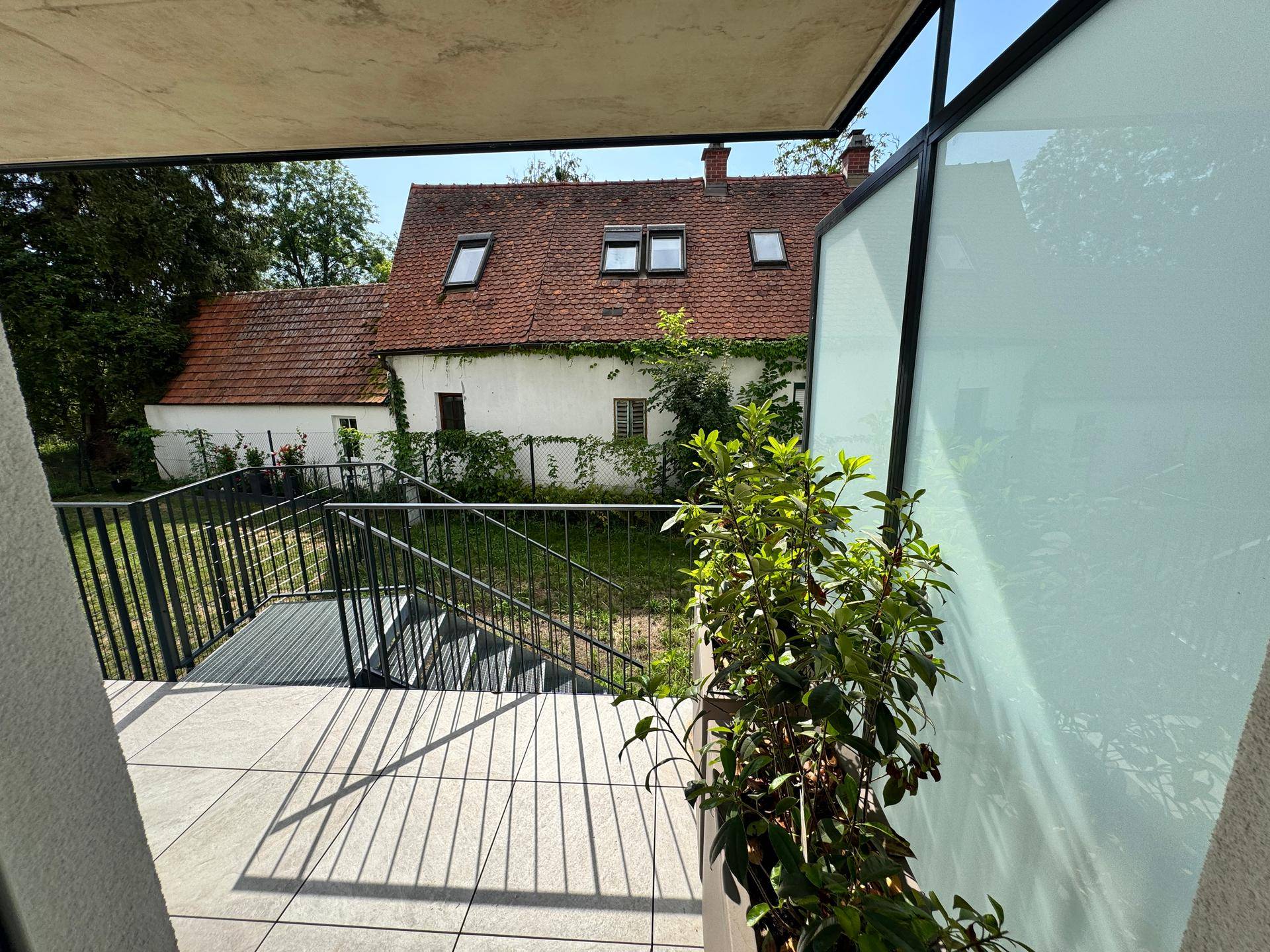 Terrasse mit Blick auf ein charmantes altes Haus und üppige Vegetation, bietet eine ruhige Atmosphäre.