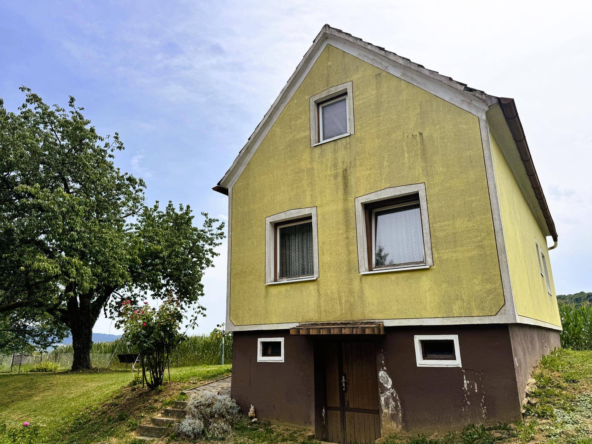 Altes gelbes Haus mit mehreren Fenstern und einem Eingang zum Kellergeschoss.