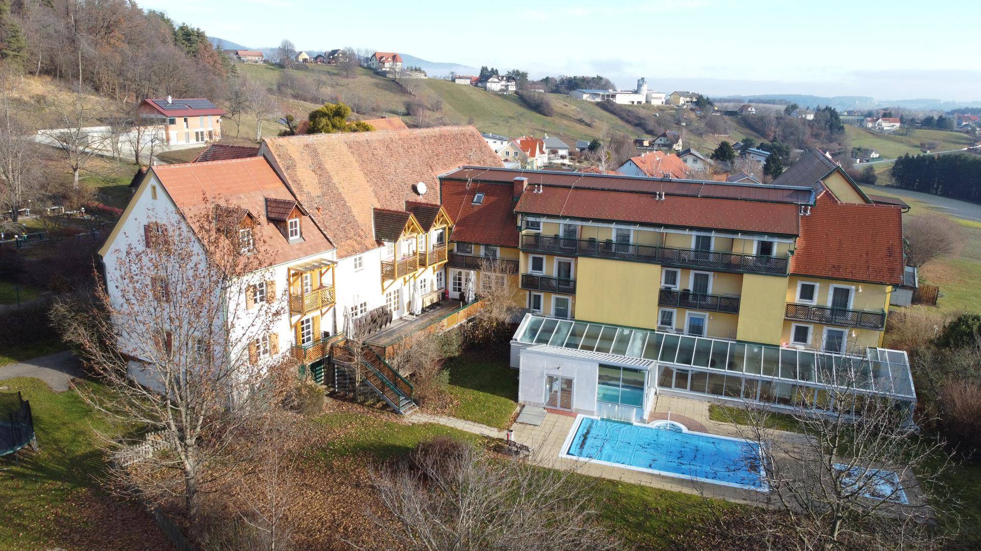 Luftaufnahme des Gebäudekomplexes mit Außenpool, Wintergarten und weitem Blick über die Landschaft.