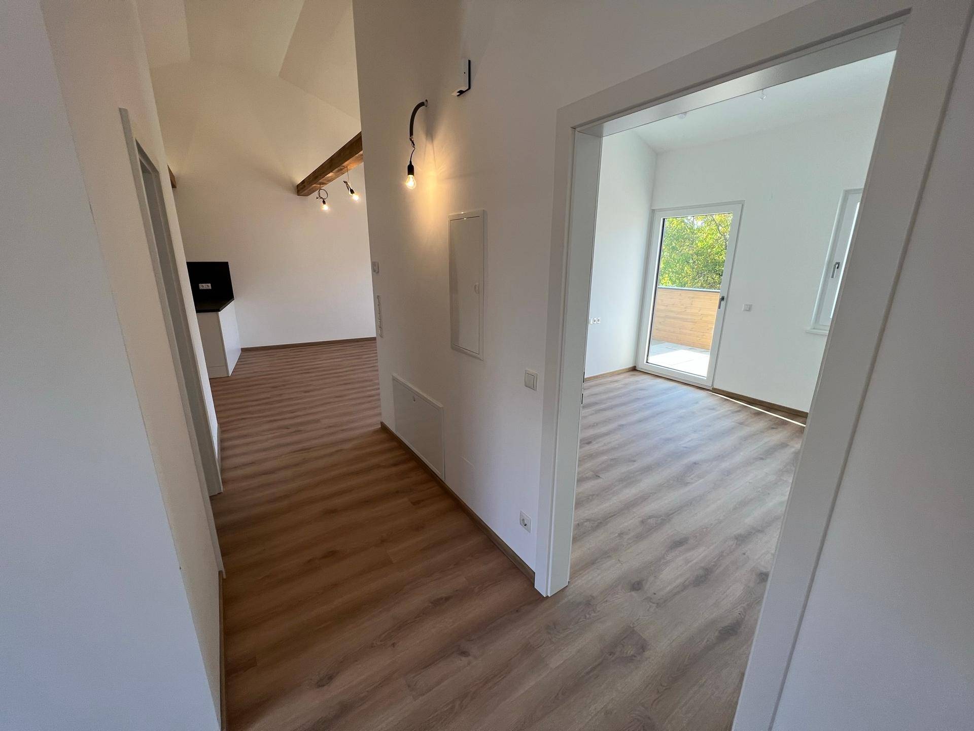 Heller Flur mit Laminatboden, der zu verschiedenen Räumen und einem offenen Wohnbereich führt.