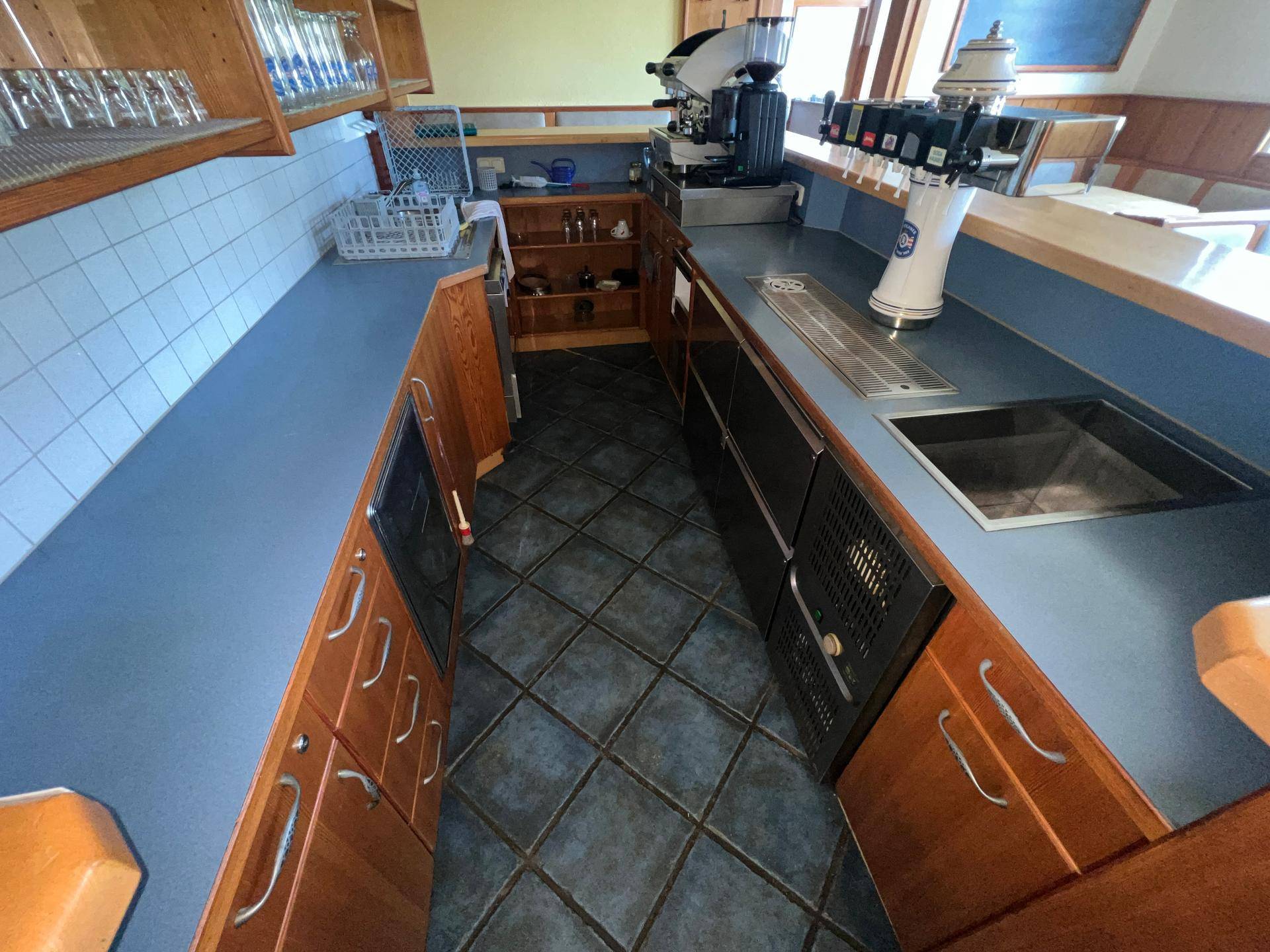 Bar-Bereich mit blauer Arbeitsplatte, Holzelementen und professioneller Kaffeemaschine.