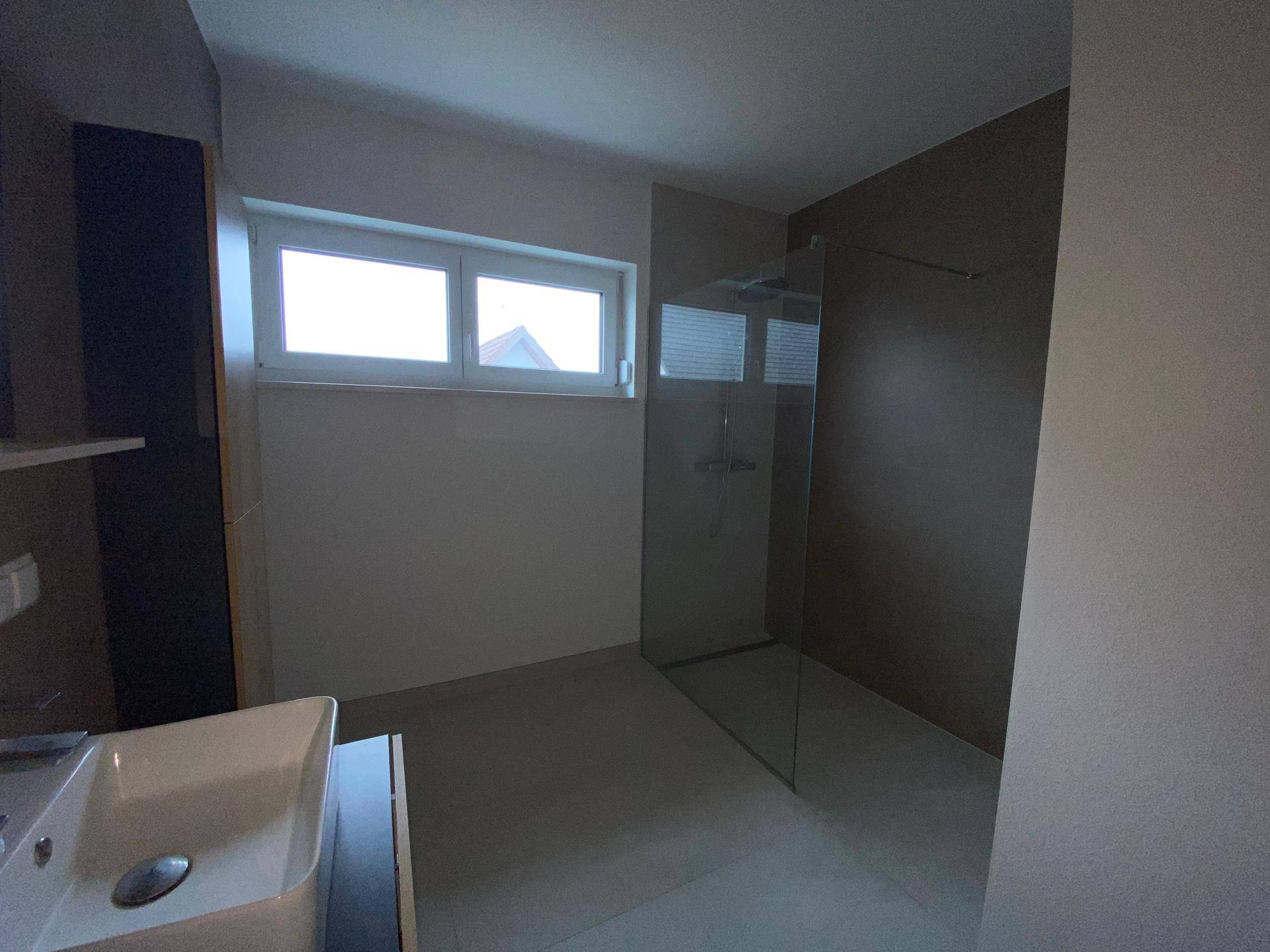 Modernes Badezimmer mit begehbarer Dusche, Fenster und stilvollen Armaturen.