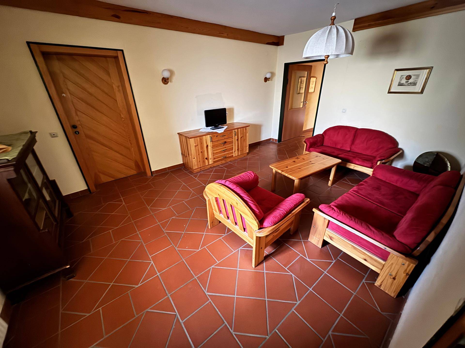 Wohnzimmer mit rustikalen Holzmöbeln und gefliestem Boden.