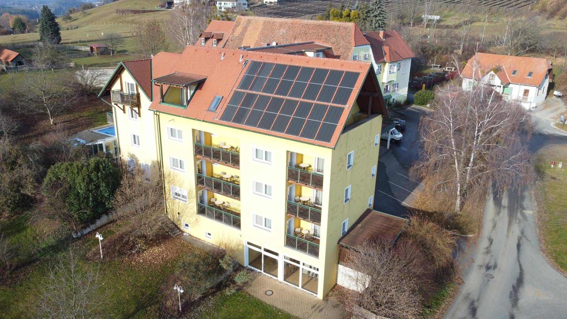 Luftaufnahme eines Gebäudeteils mit Solaranlagen auf dem Dach und Balkonen.