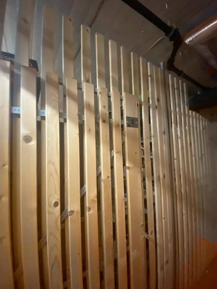 Detailansicht eines Kellerabteils mit vertikalen Holzlatten zur Lagerung.