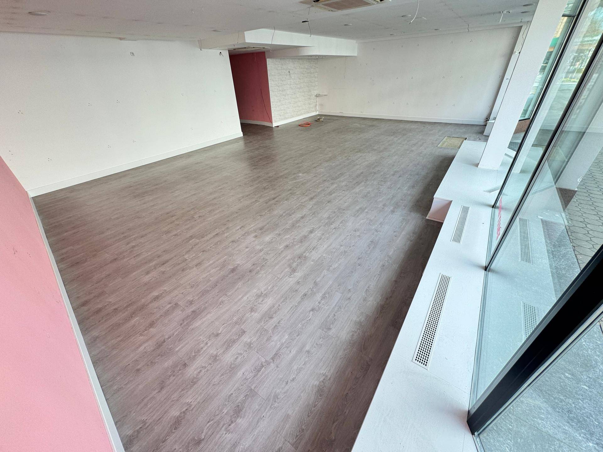 Weitläufiger Ladenbereich mit Laminatboden und großen Schaufenstern für optimale Präsentation.