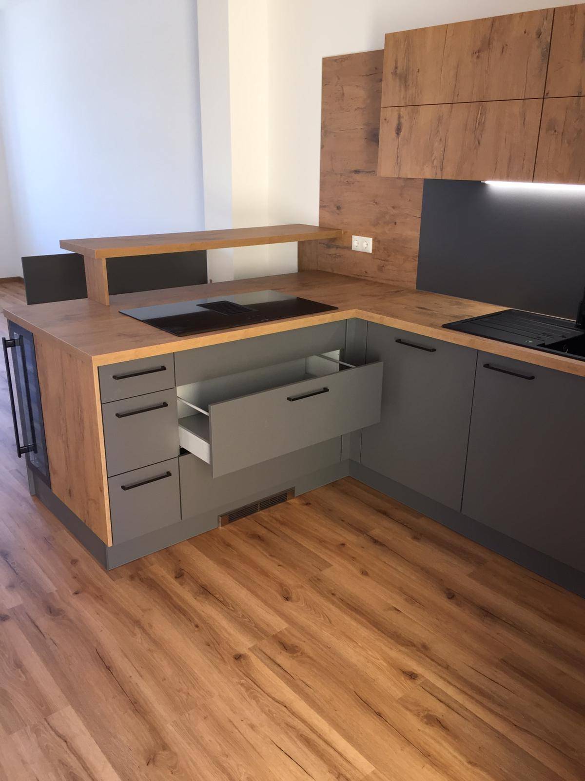 Detailansicht der modernen Küche mit Holzoptik-Arbeitsplatten und grauen Schubladen.