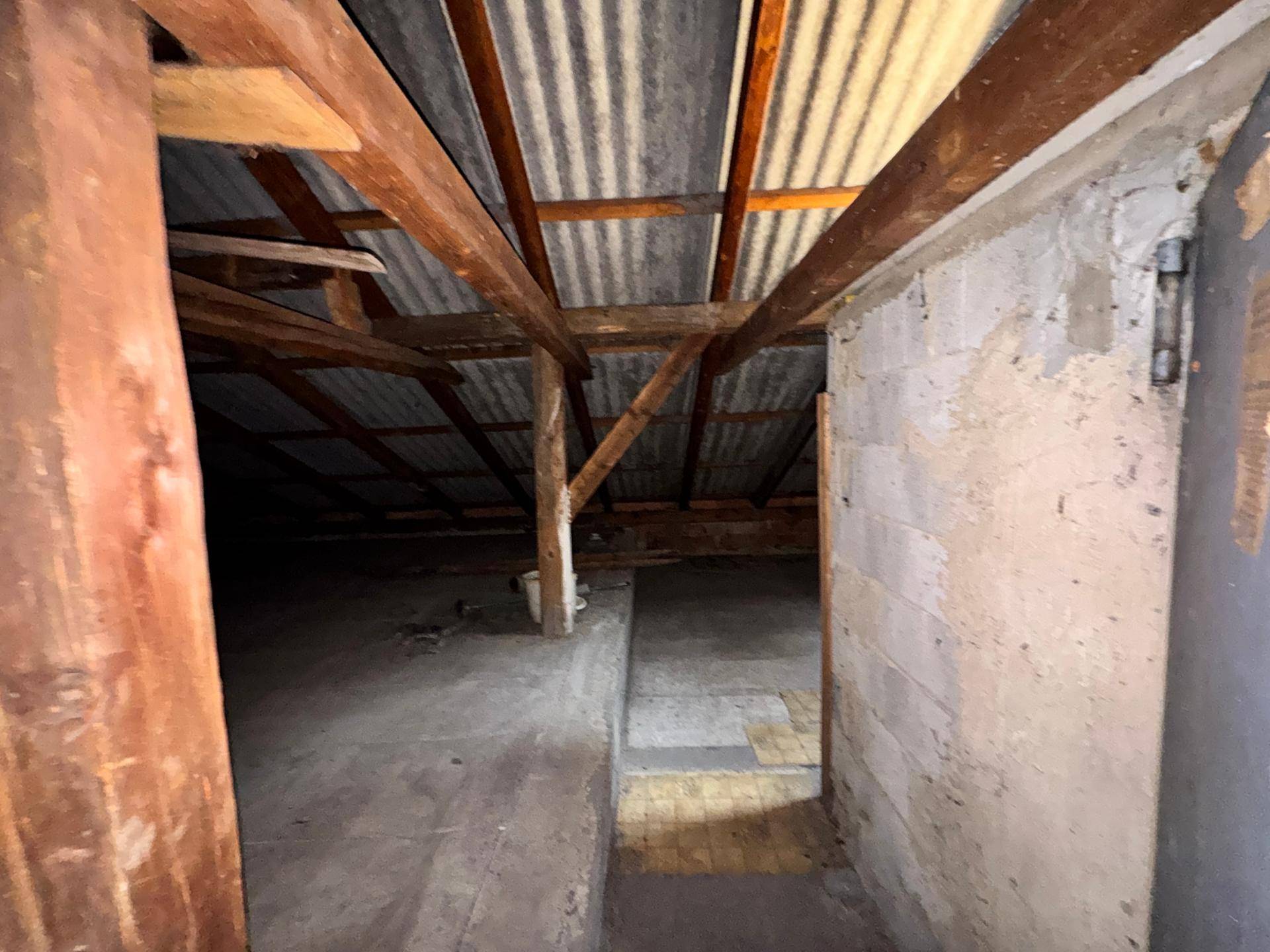 Unausgebauter Dachboden mit sichtbaren Holzbalken und unfertiger Dachkonstruktion, ideal als Stauraum.