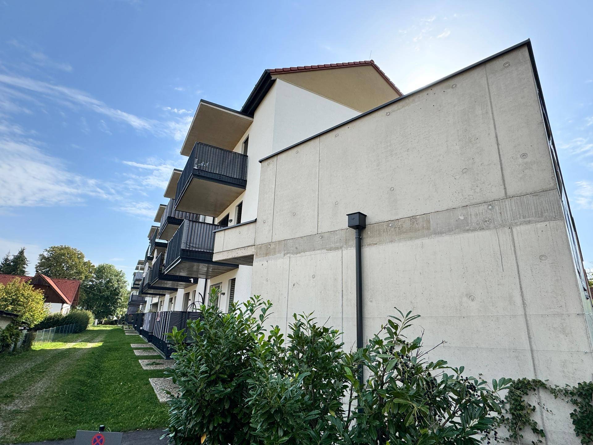 Seitenansicht des modernen Gebäudes mit markanter Betonfassade und mehreren Balkonen.