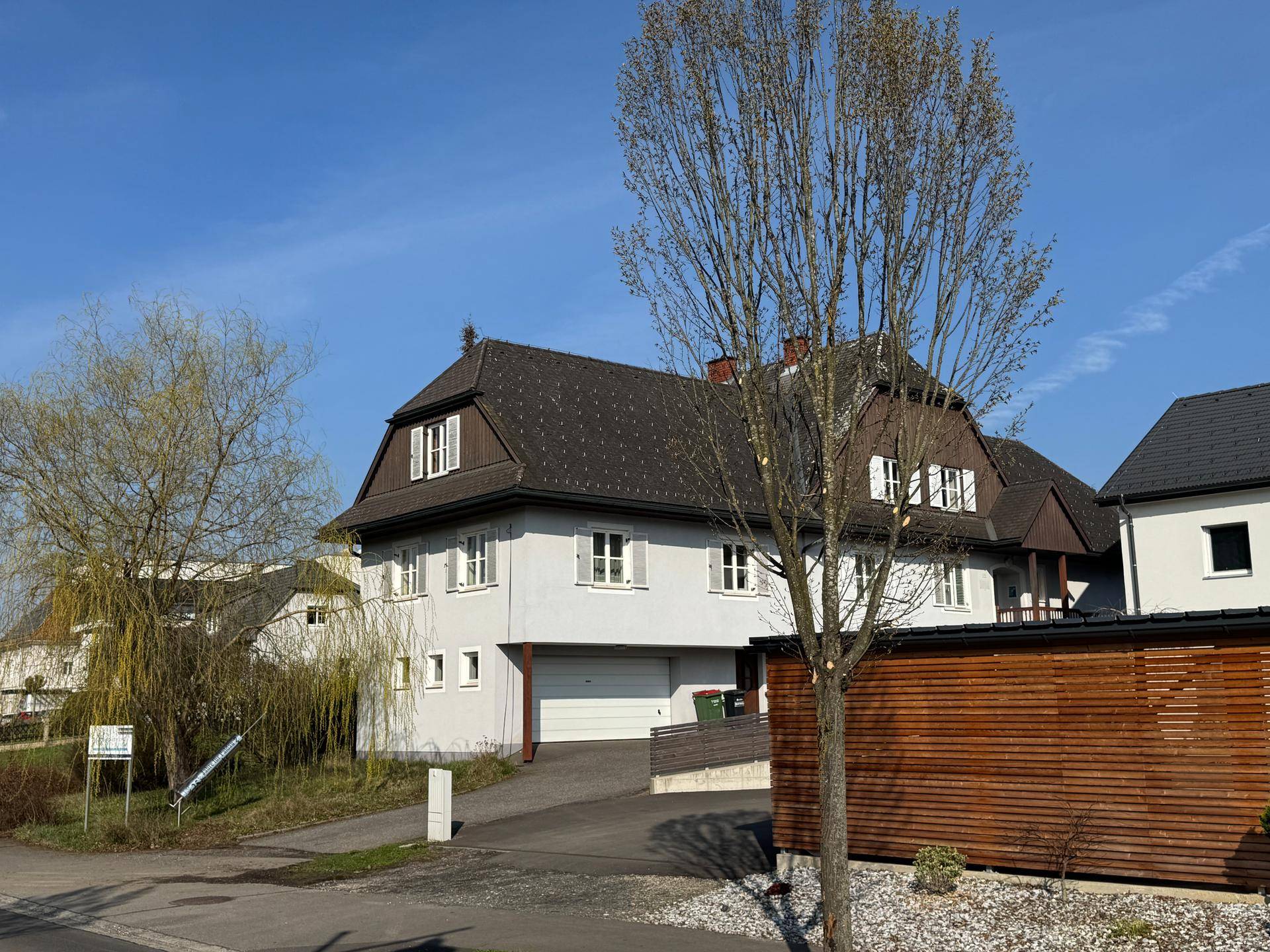 Vorderansicht des Hauses mit integrierter Garage, Mansarddach und Zufahrt.