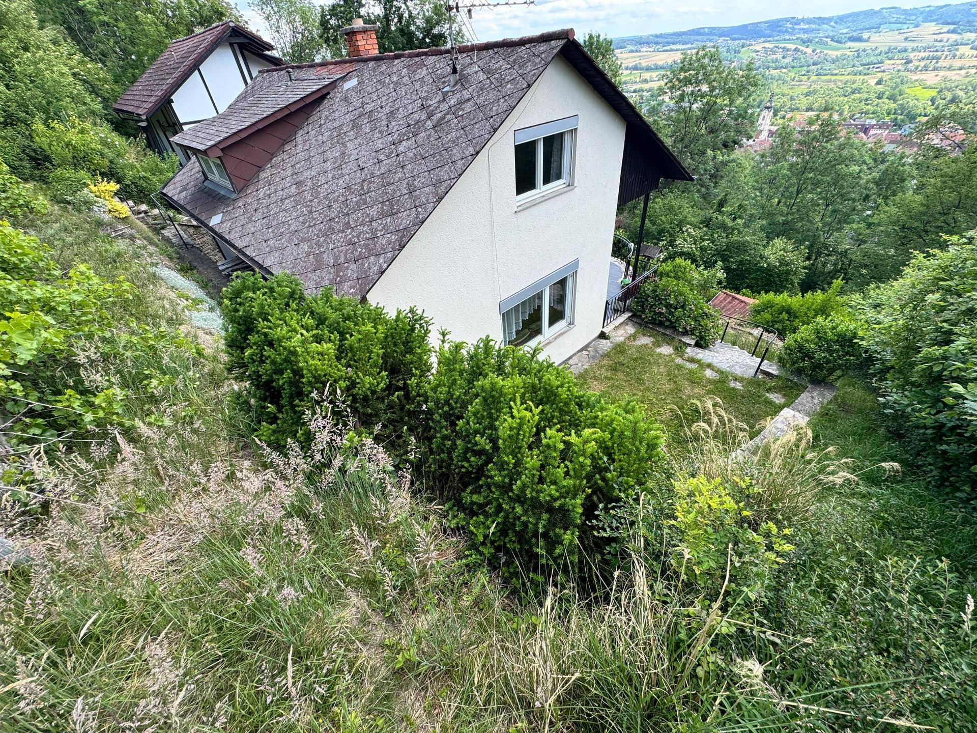 Vogelperspektive des Hauses mit Satteldach, umgeben von viel Grün und einer weiten Landschaft.