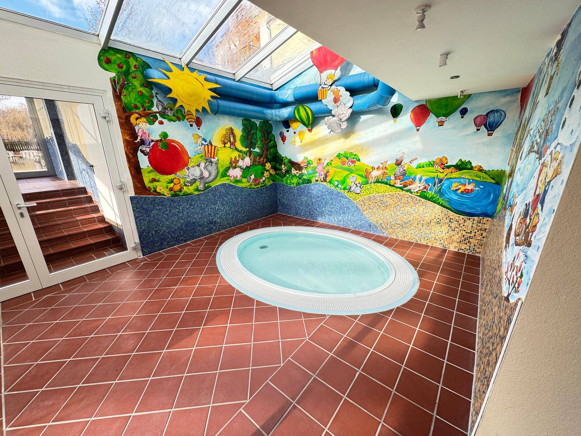 Kinderpoolbereich mit farbenfrohen Wandmalereien und Whirlpool.