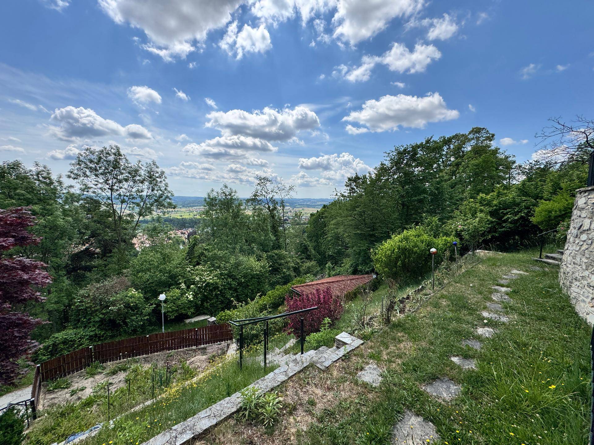 Terrassierter Gartenbereich mit Steinstufen und weitem Blick über die grüne Hügellandschaft.