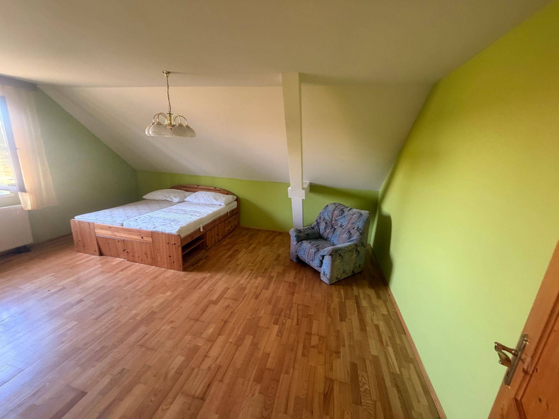 Schlafzimmer im Dachgeschoss mit Holzboden, grünen Wänden und Doppelbett.