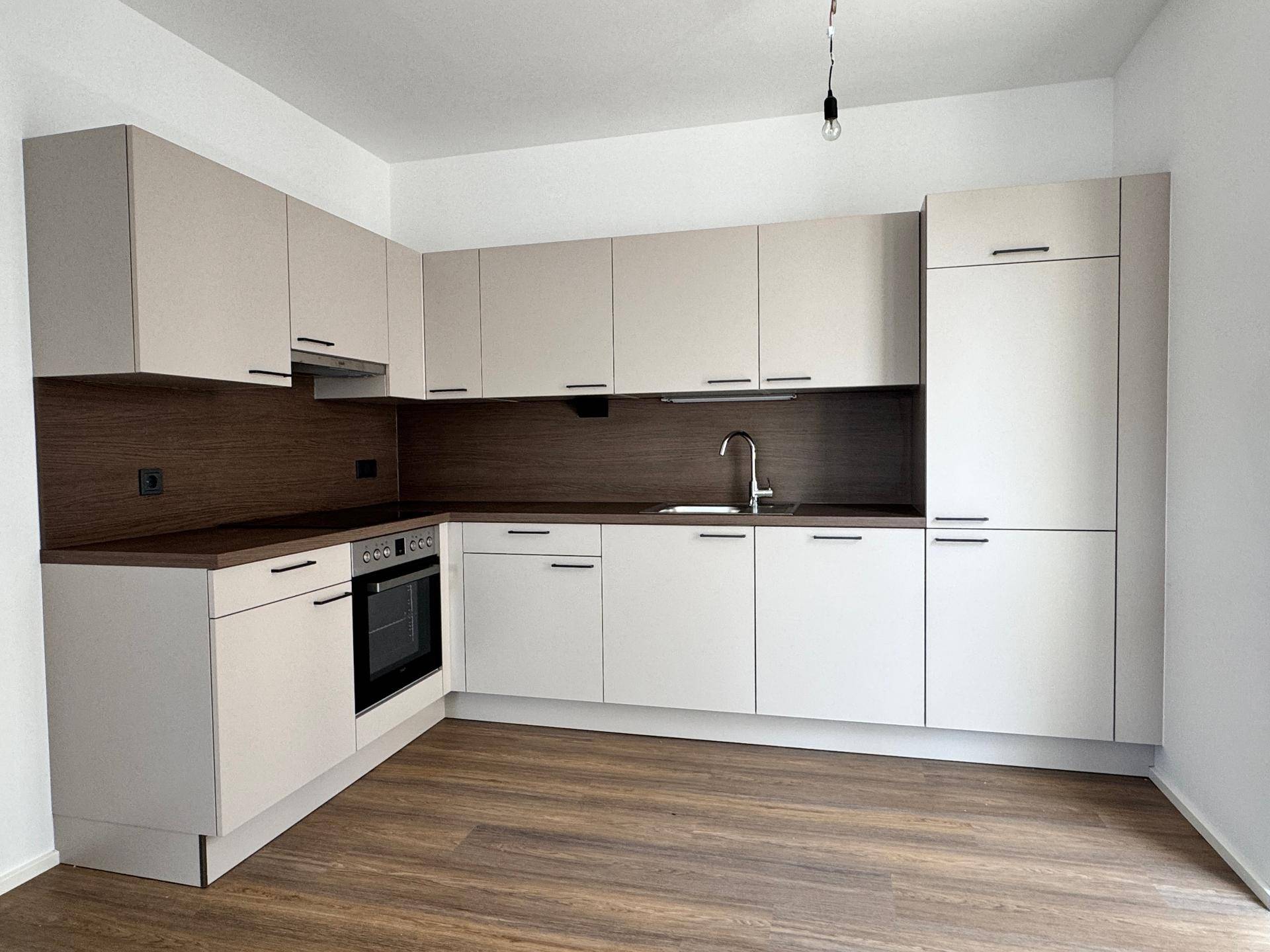Moderne Einbauküche in hellem Beige mit dunkler Arbeitsplatte und integrierten Elektrogeräten.