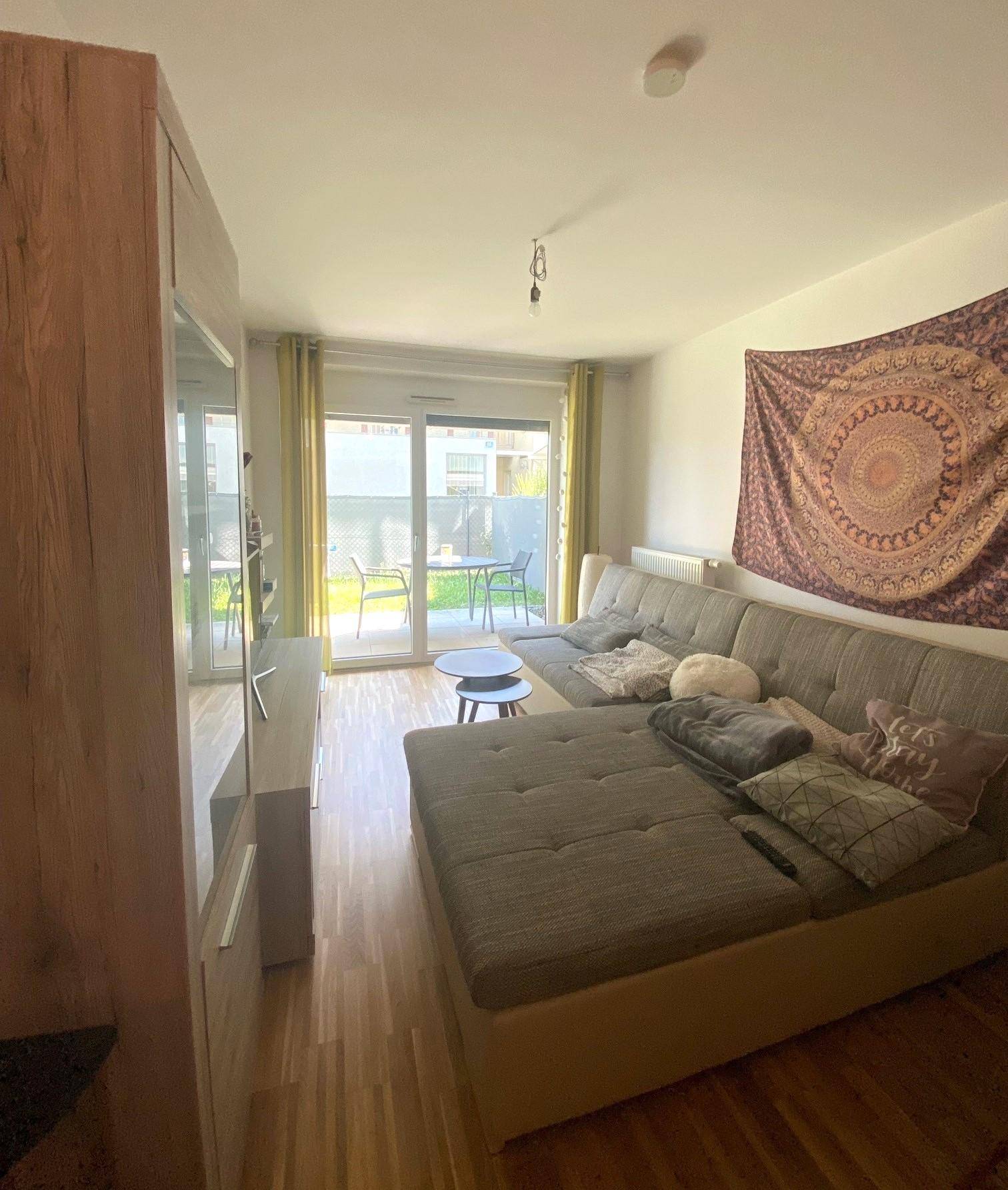 Gemütliches Wohnzimmer mit großem Ecksofa, Holzboden und Zugang zur Terrasse.