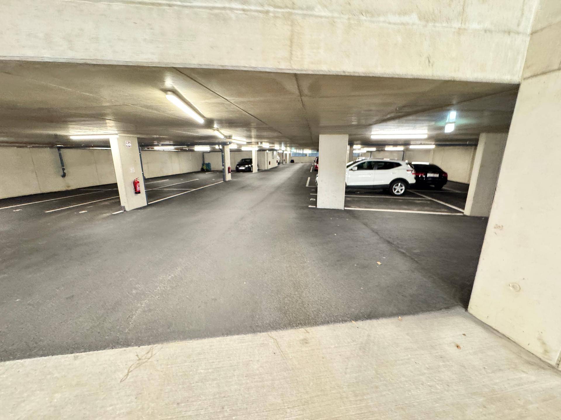 Weitläufige Tiefgarage mit mehreren Parkplätzen und guter Beleuchtung.