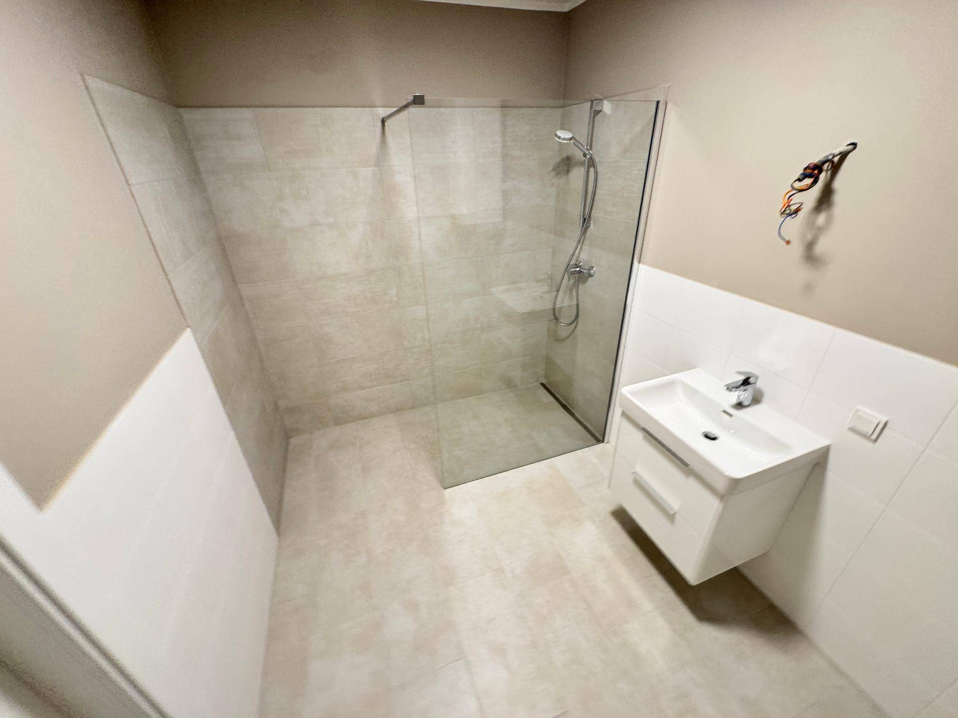 Modernes Badezimmer mit begehbarer Dusche und weißem Waschbeckenunterschrank, funktional und hell.