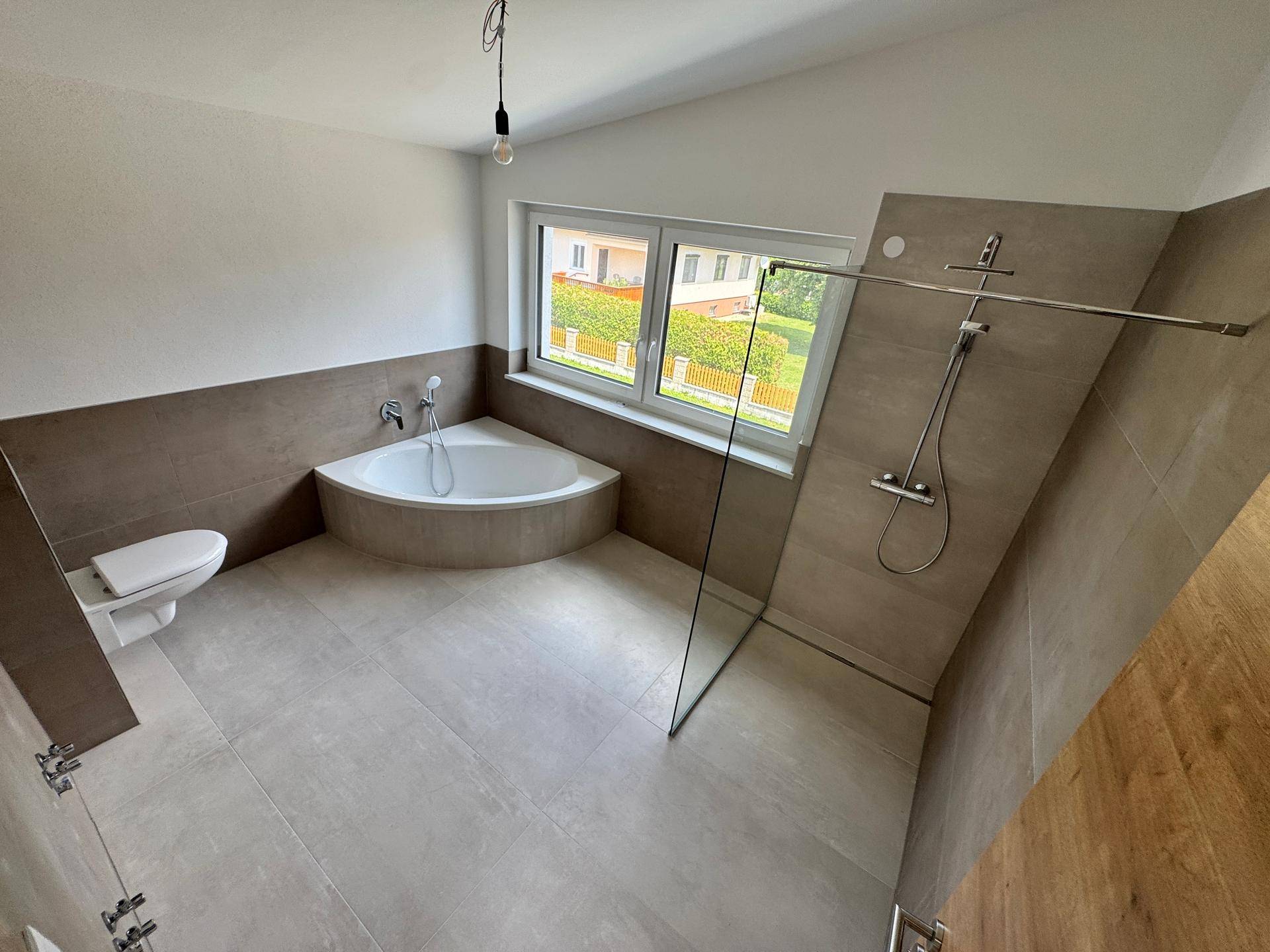 Modernes Badezimmer mit Eckbadewanne, ebenerdiger Dusche und wandhängendem WC.