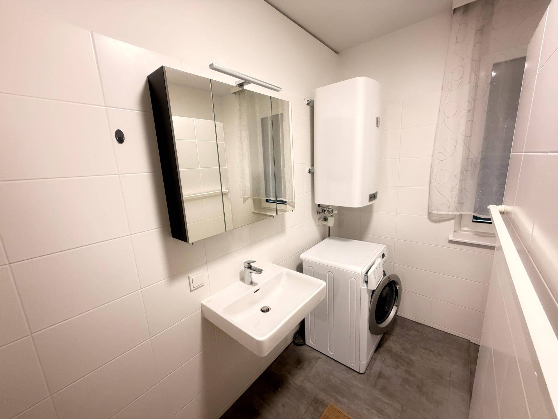Modernes Badezimmer mit Waschbecken, Spiegelschrank und Boiler.