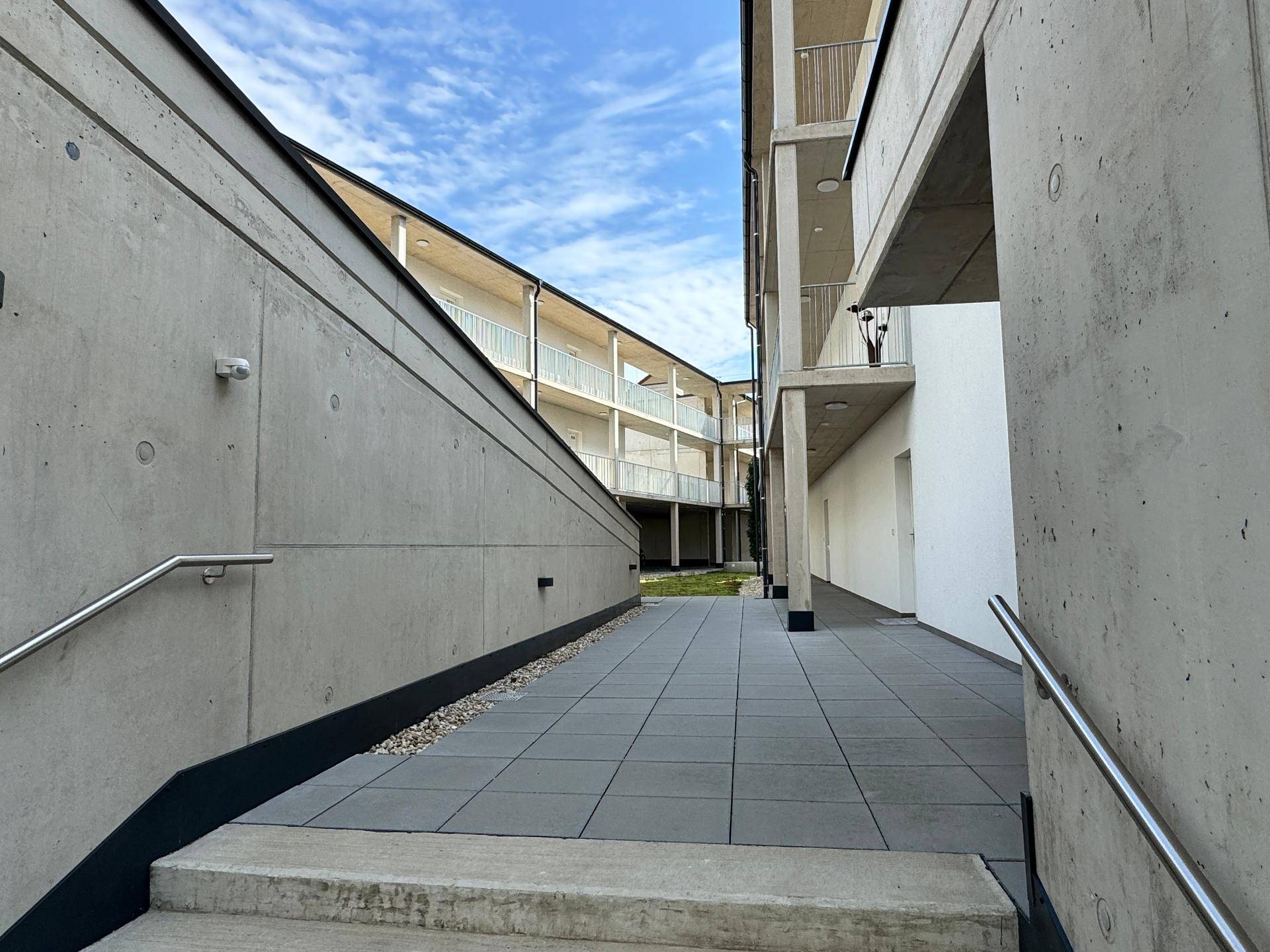 Außenansicht eines modernen Wohnkomplexes mit klaren Linien und Balkonen unter blauem Himmel.