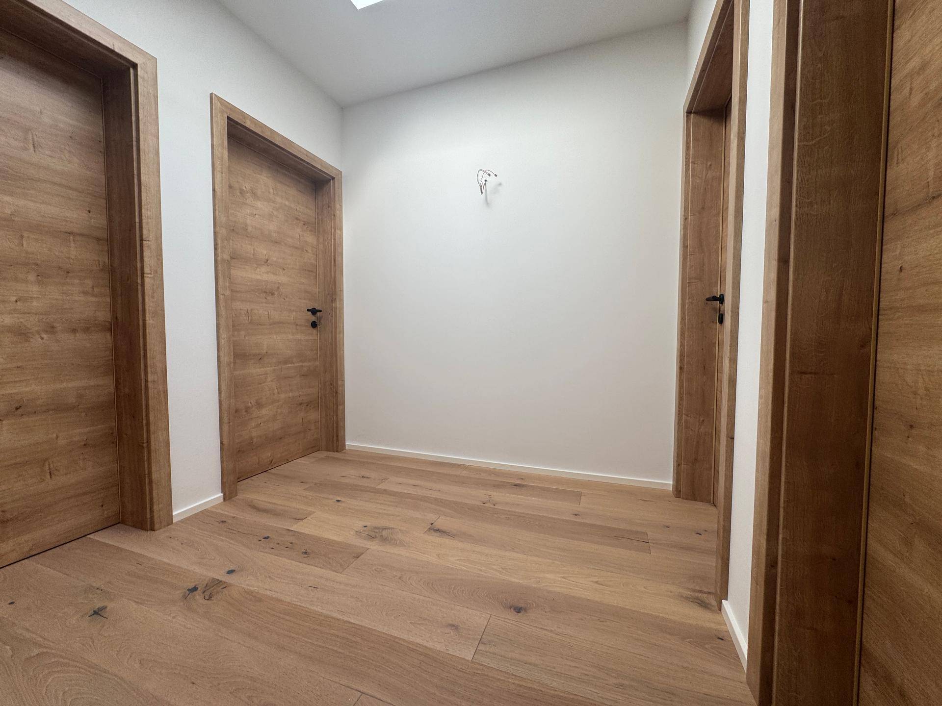 Heller Flur im Obergeschoss mit Eichenparkett, Holztüren und Oberlicht.