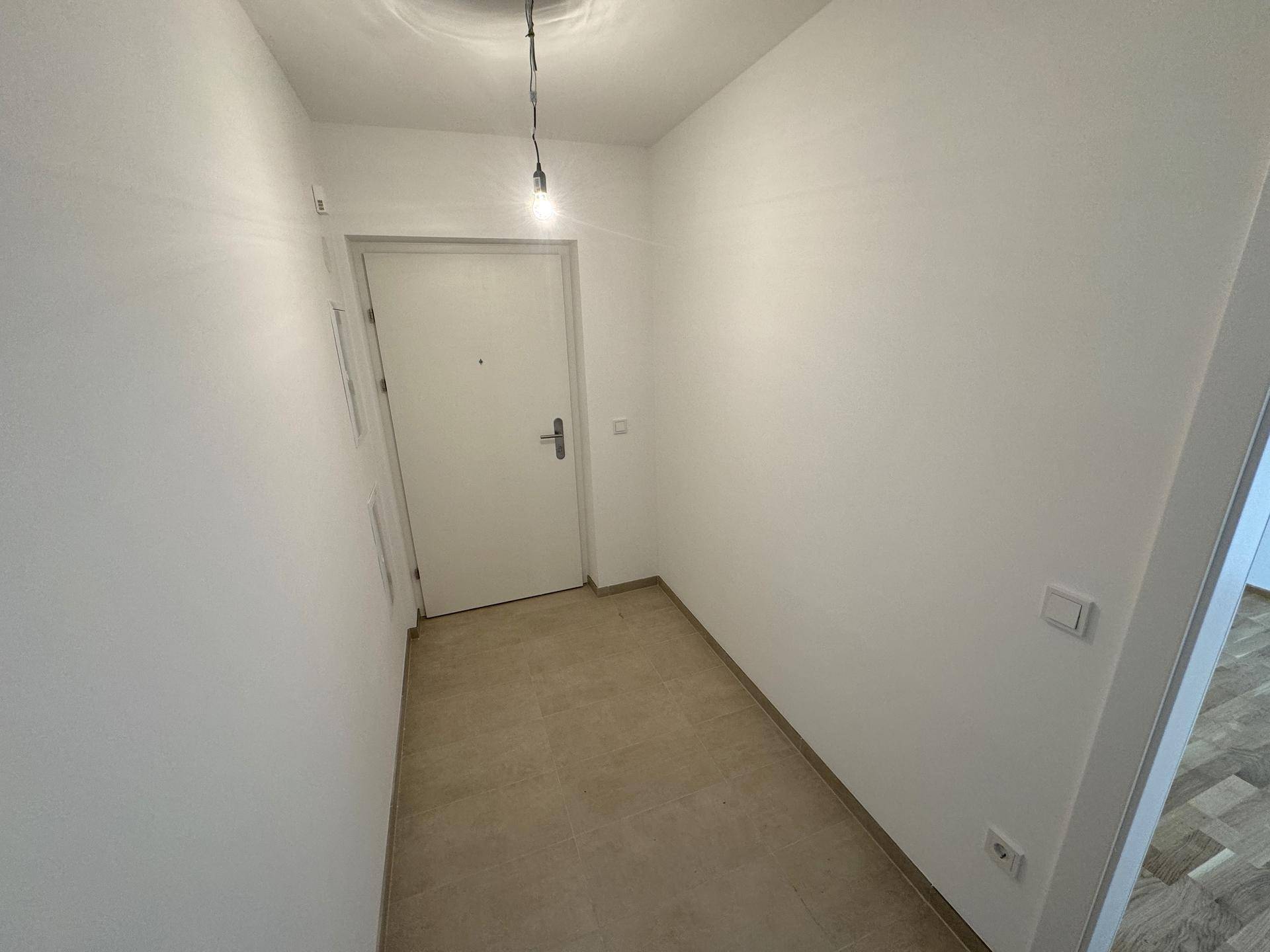 Heller Eingangsbereich mit Fliesenboden und weiß gestrichenen Wänden.