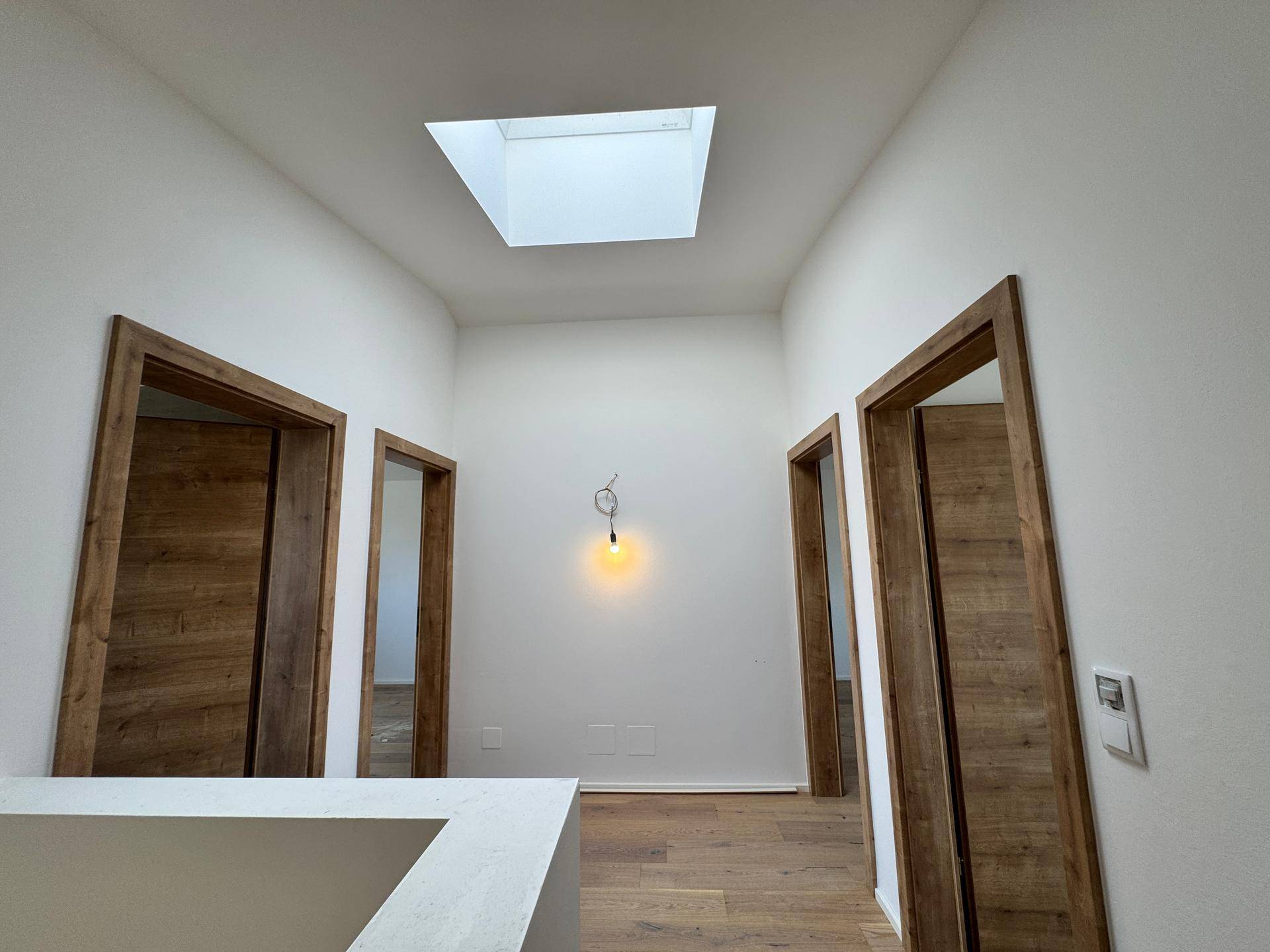 Obergeschossflur mit Holzboden und einem Oberlicht, das den Bereich mit natürlichem Licht durchflutet.