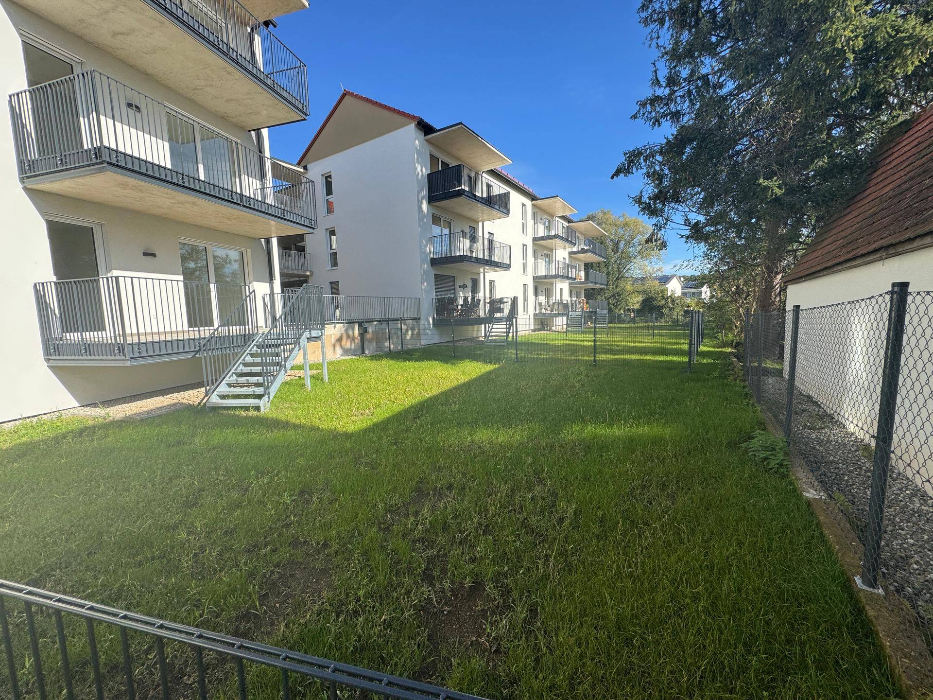 Zufahrt zur Tiefgarage mit Ziegelmauerwerk und asphaltiertem Vorplatz.