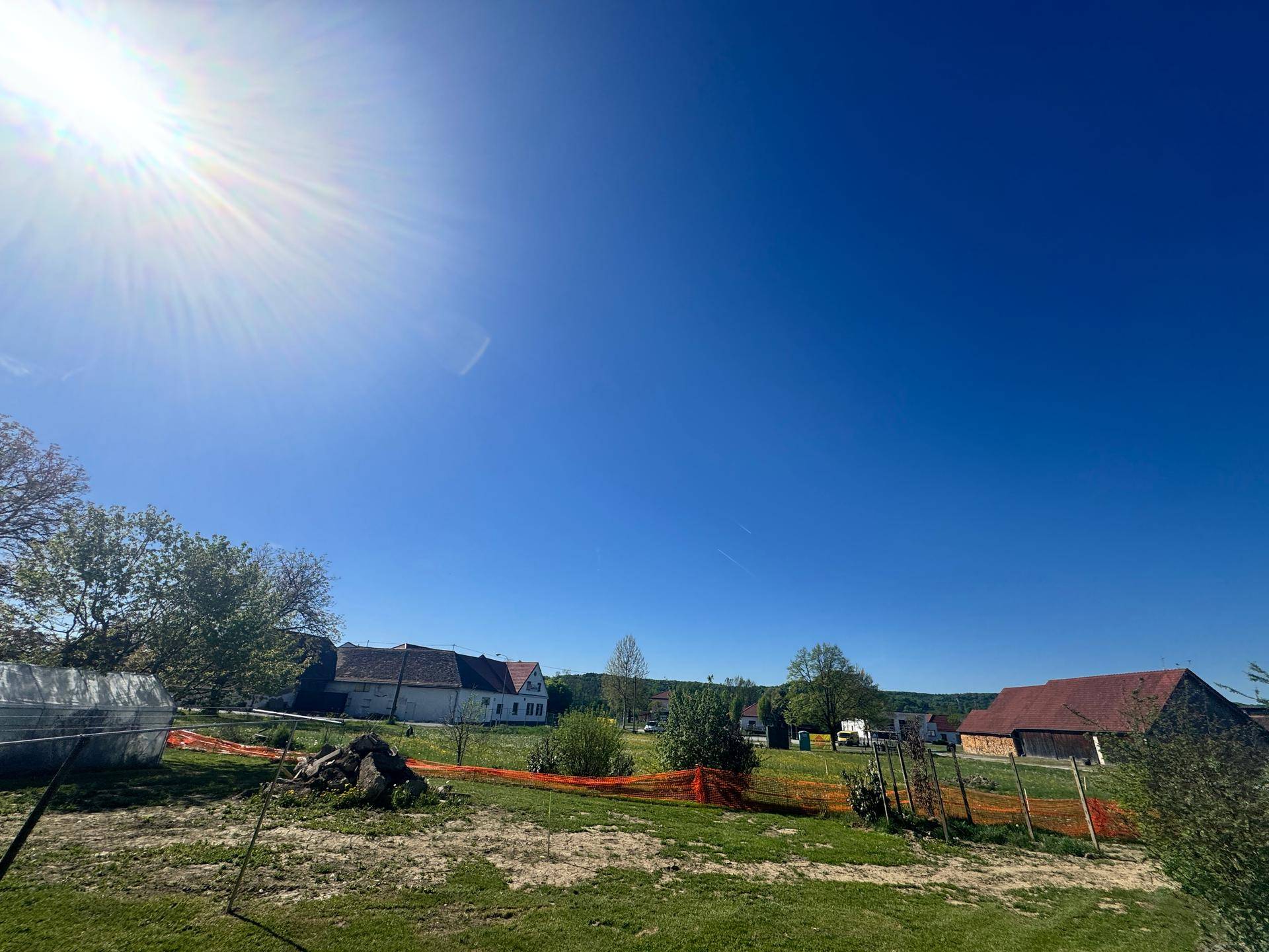 Sonniges Grundstück mit weitem Blick auf die ländliche Umgebung und entfernte Gebäude.