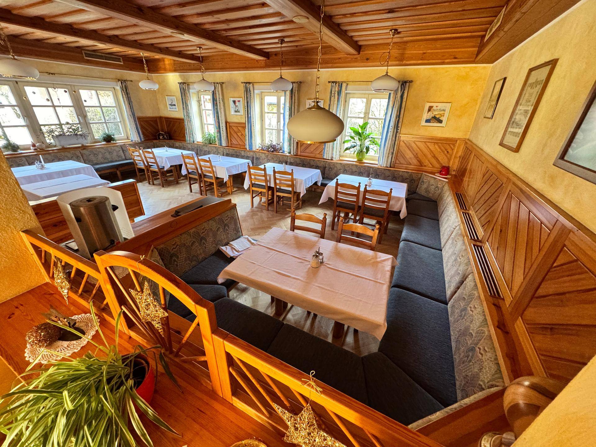 Gemütlicher Speisesaal mit Holztäfelung, Sitzbänken und Blick nach draußen.
