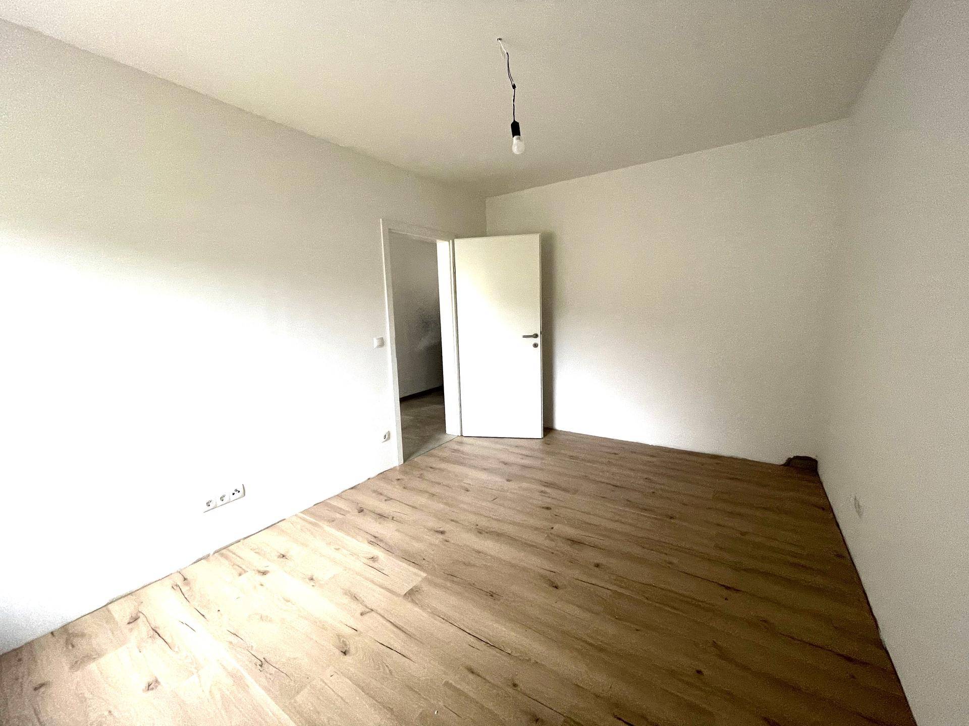 Geräumiges Schlafzimmer mit hellem Laminatboden und weiß gestrichenen Wänden, bereit zum Einrichten.