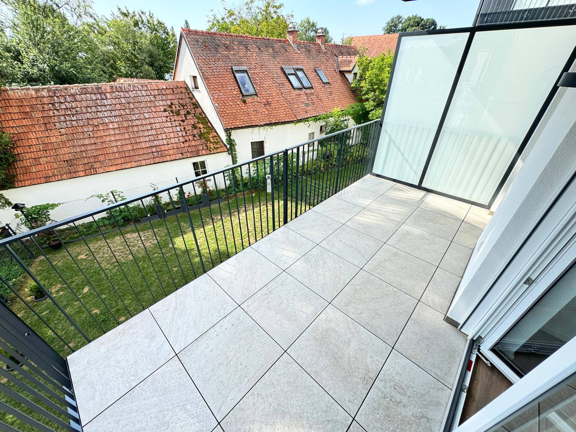 Geräumiger Balkon mit Fliesenboden und Metallgeländer, bietet einen Blick auf die Umgebung.