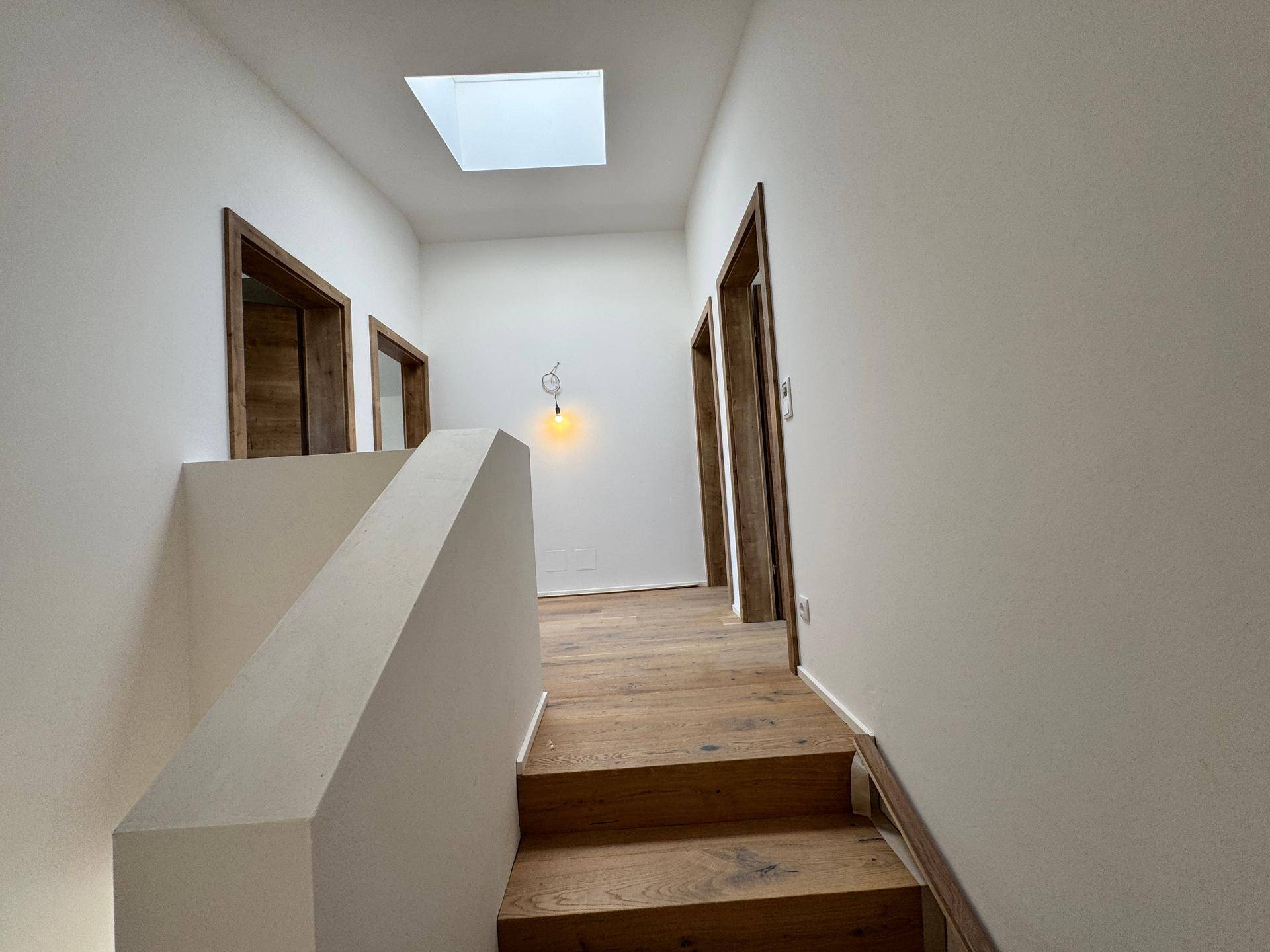 Heller Flur im Obergeschoss mit Holzboden und einem Oberlicht, das für zusätzliche Helligkeit sorgt.