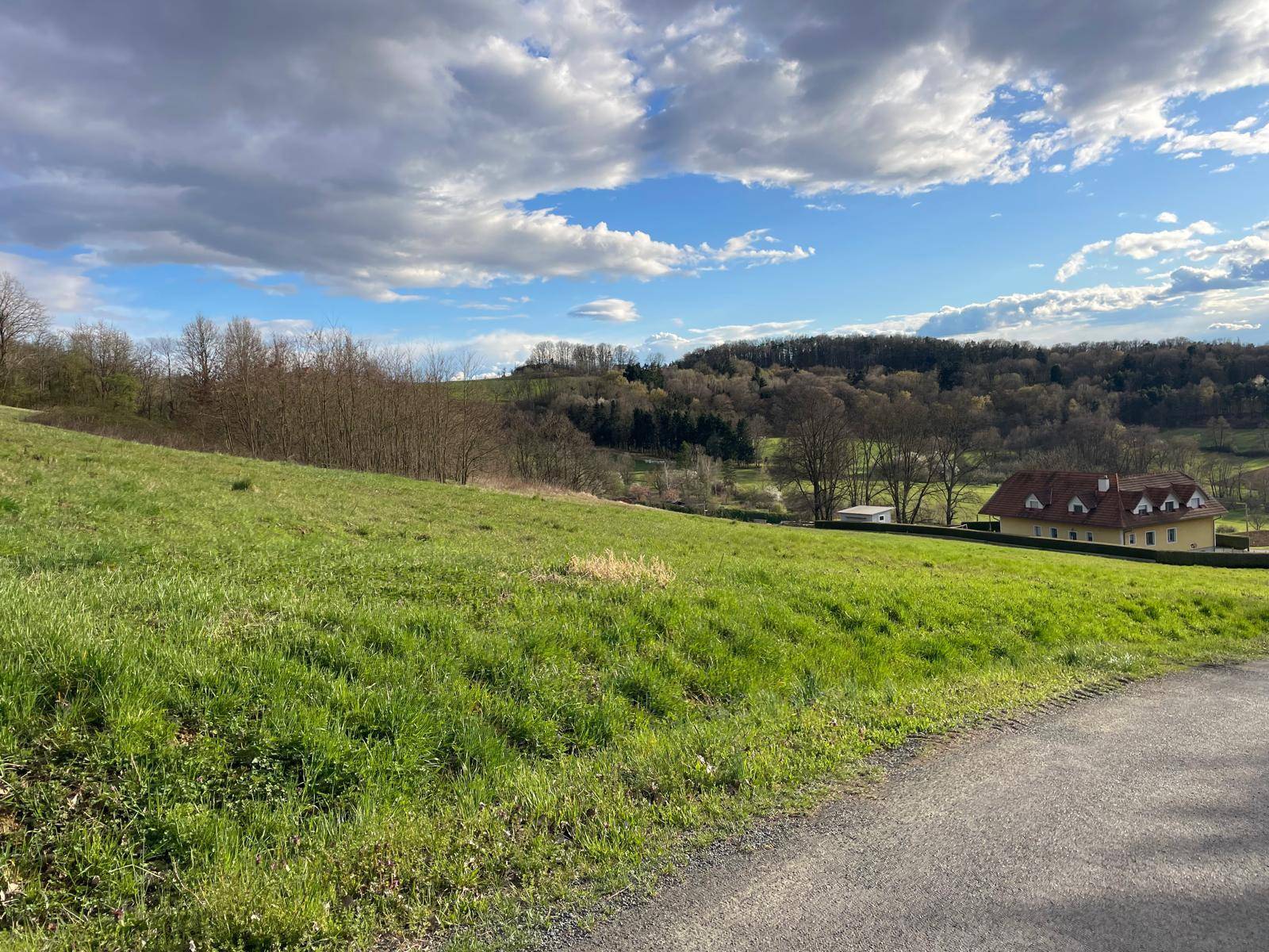 Grüne Hügellandschaft mit einem traditionellen Haus und weitem Blick auf die Umgebung.