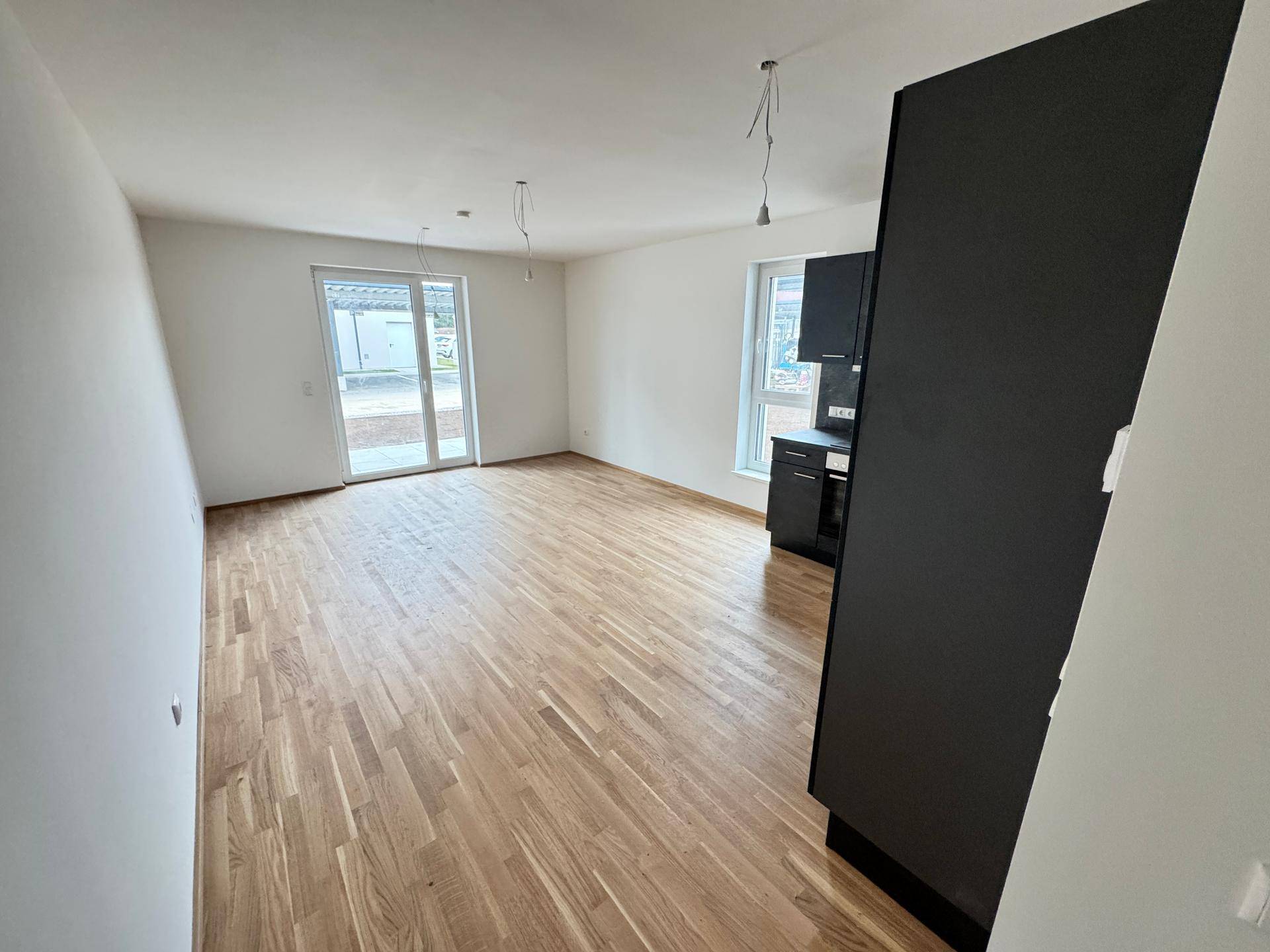 Heller Wohnbereich mit Parkettboden und Zugang zu einer Terrasse, ideal für den Außenbereich.