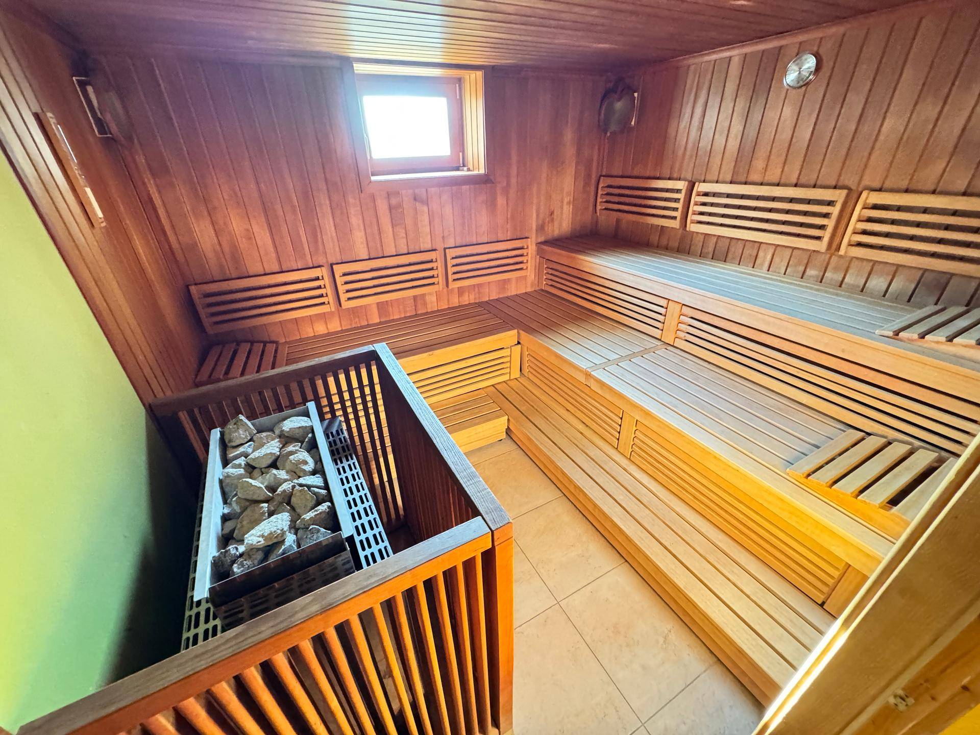 Geräumige Sauna mit Holzverkleidung, Sitzbänken und Heizofen.