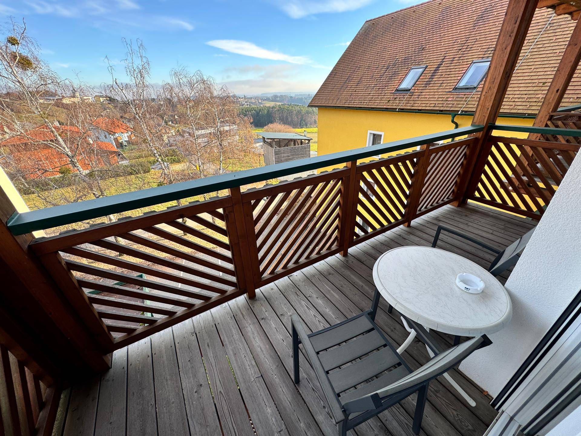 Balkon mit Holzboden, Sitzgelegenheiten und weitem Blick über die Landschaft.