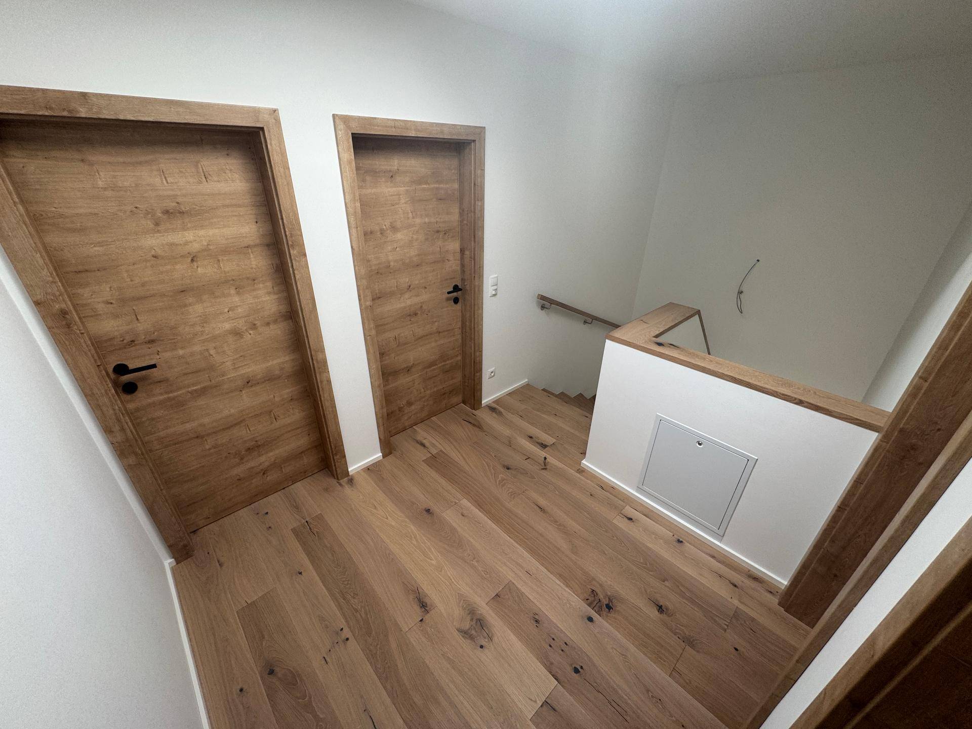 Flur im Obergeschoss mit Eichenparkett, Holztüren und Treppengeländer.