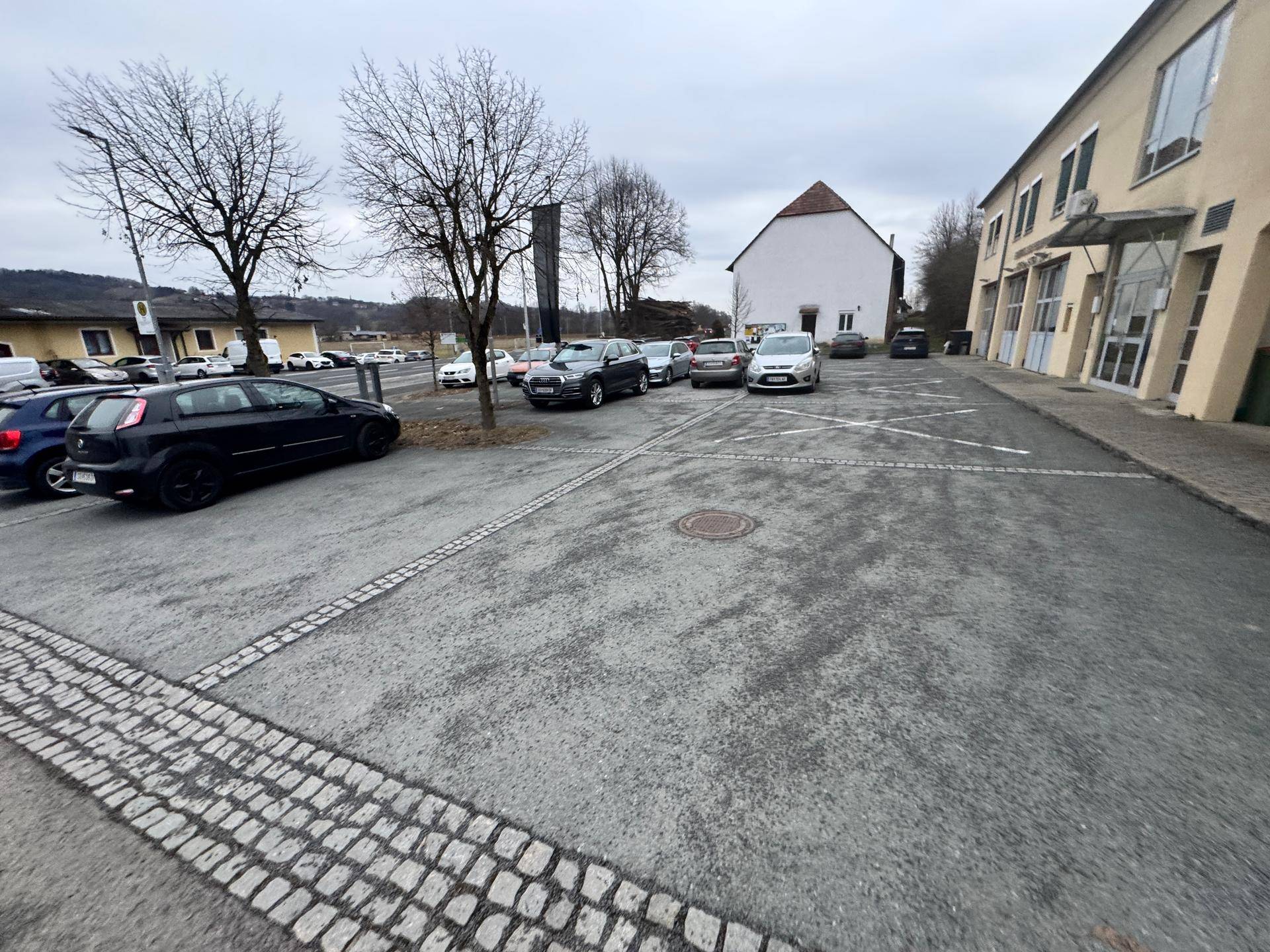 Außenbereich mit Parkplätzen vor einem Gebäude an einem bewölkten Wintertag.