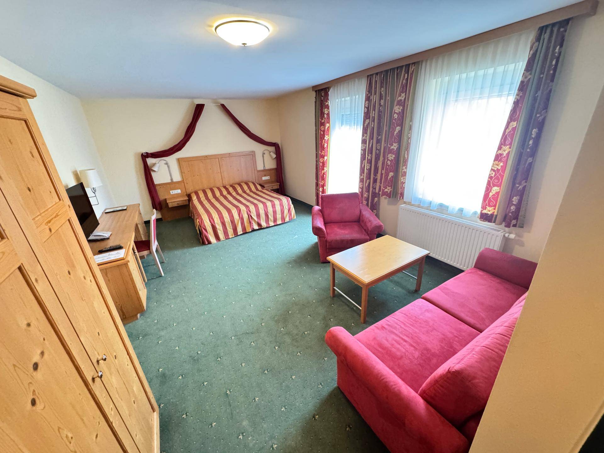 Schlafzimmer mit Doppelbett, Sofa und Teppichboden.