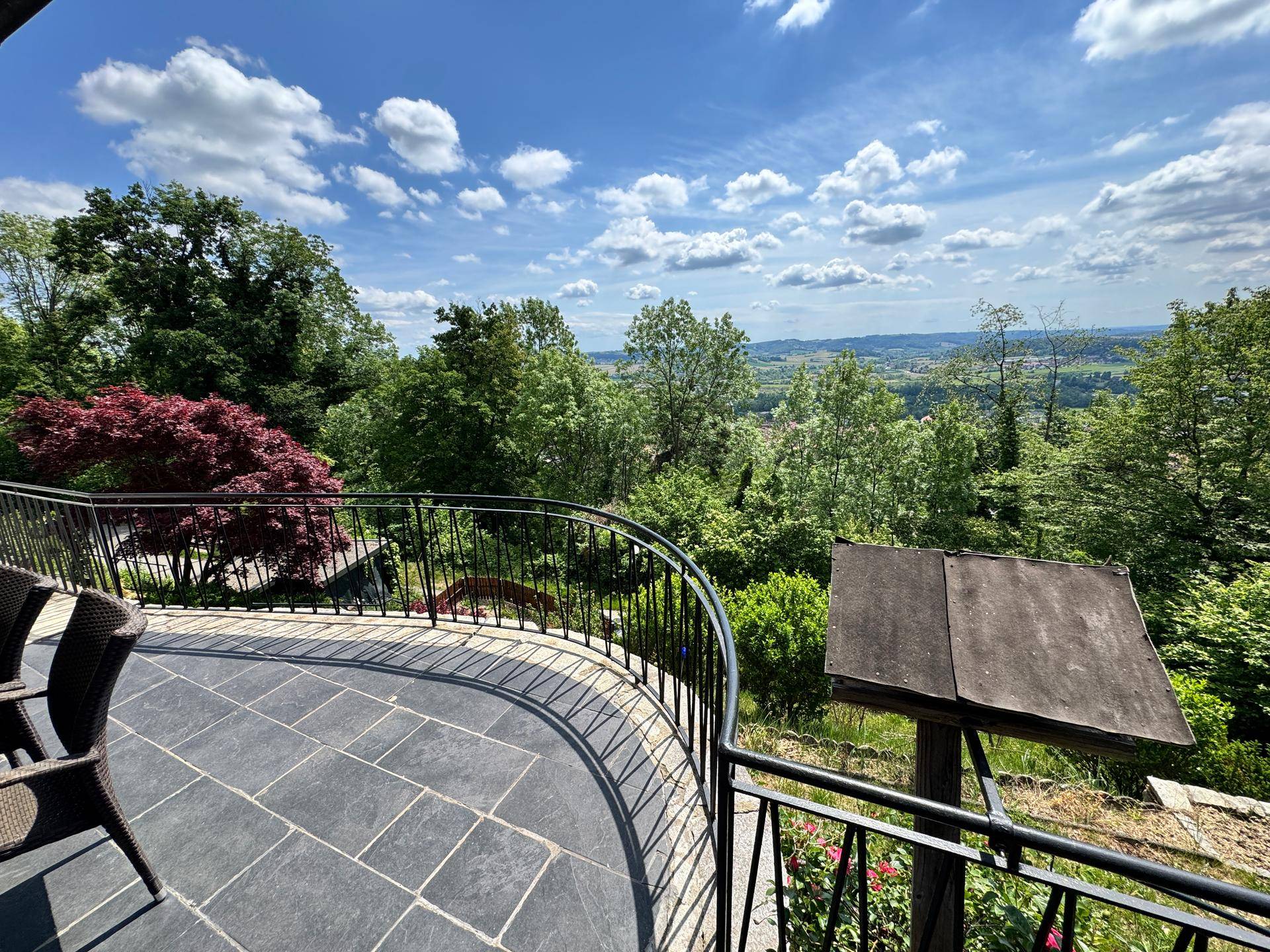 Balkon mit schmiedeeisernem Geländer und weitem Blick über die grüne Hügellandschaft.