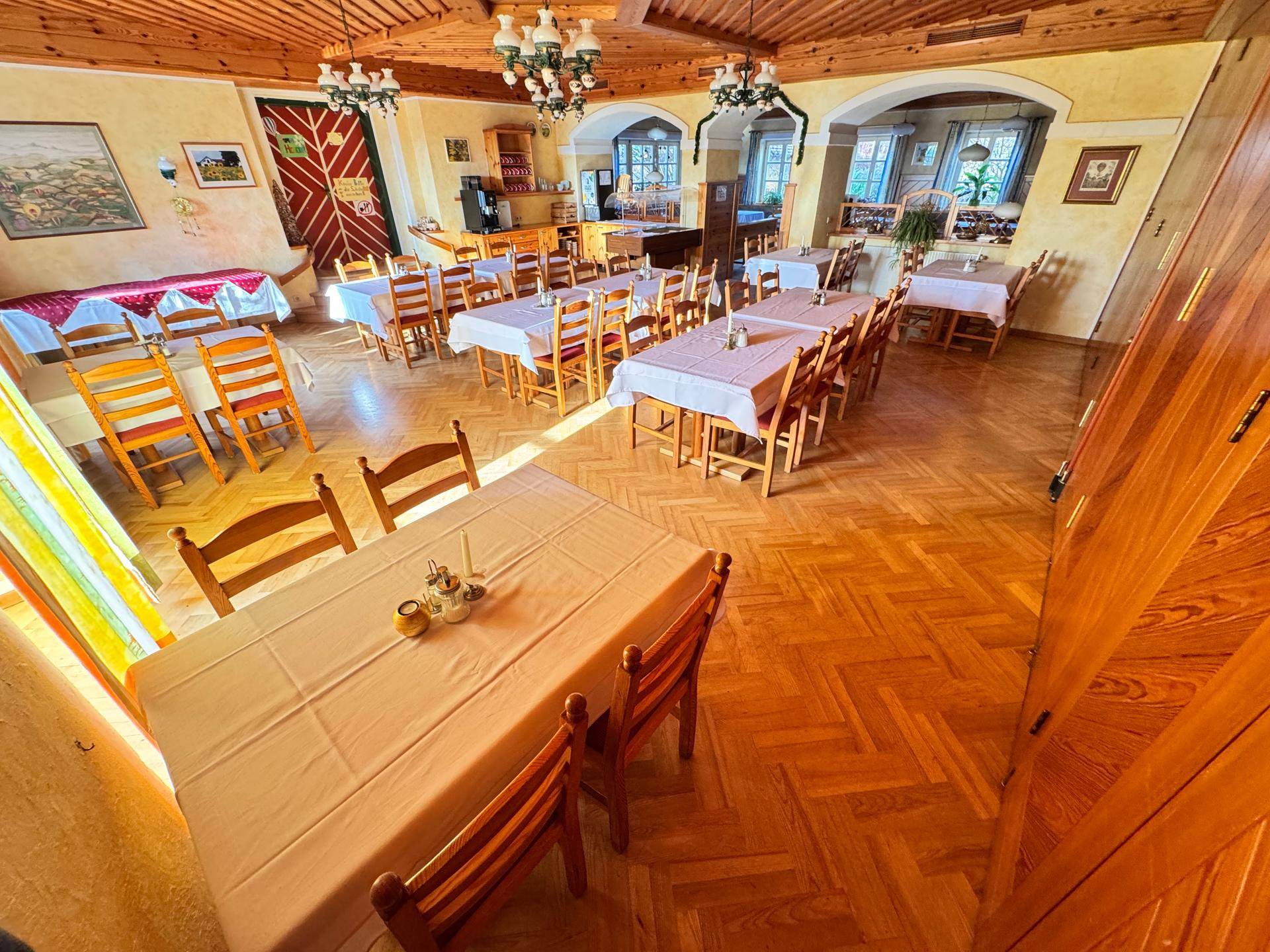 Geräumiger Speisesaal mit Holzboden, gedeckten Tischen und traditioneller Einrichtung.