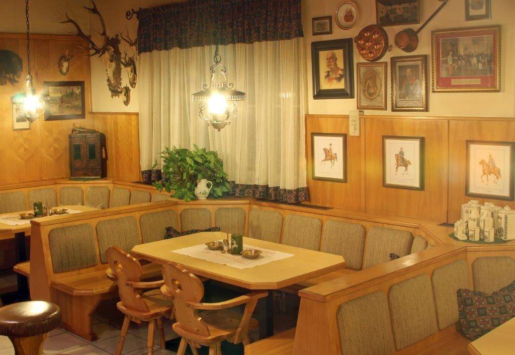 Gemütliche Sitzecke mit Holztischen, gepolsterten Bänken und traditioneller Dekoration.