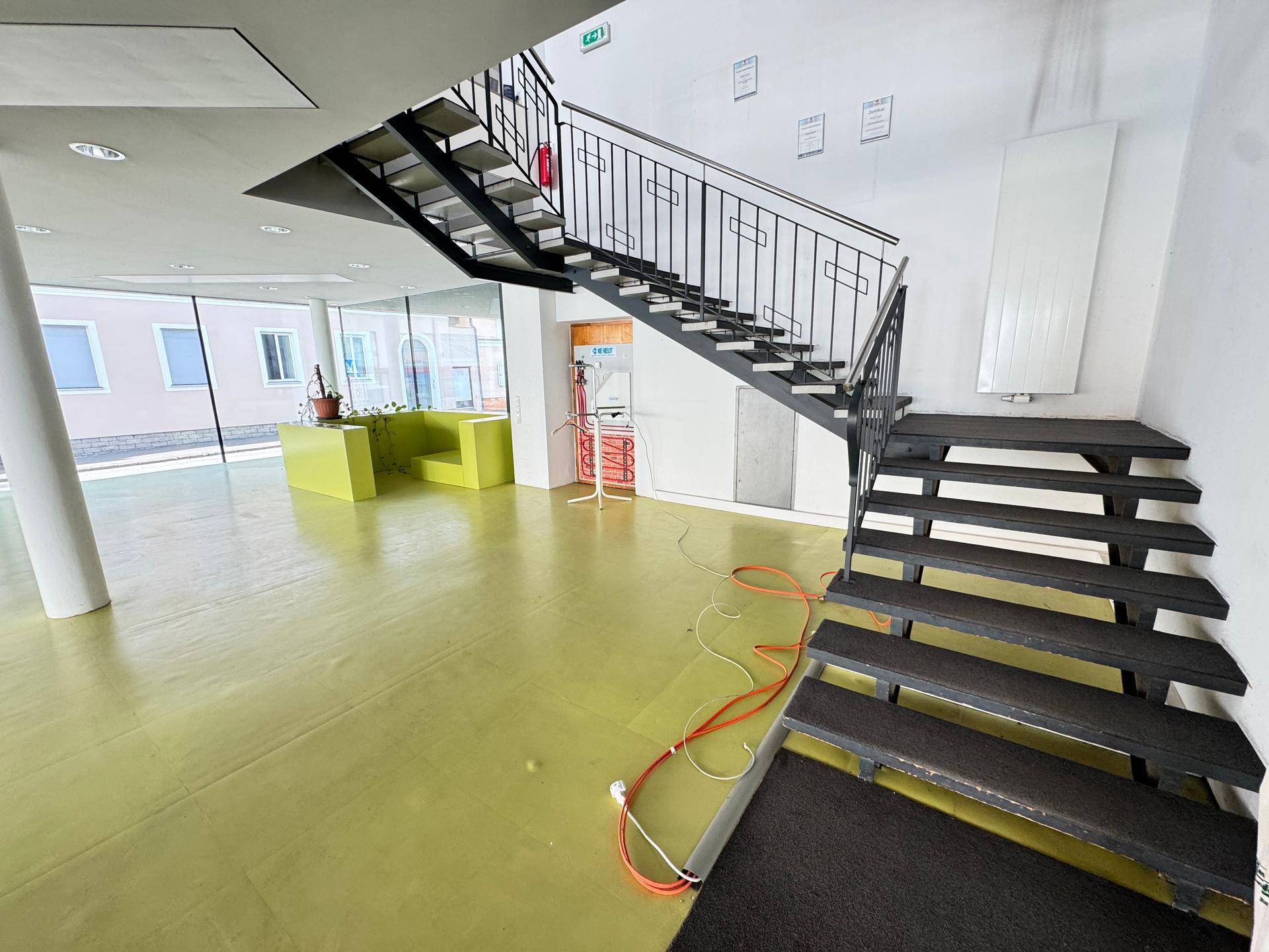 Geräumiger Eingangsbereich mit Treppe, großen Fenstern und hellem Bodenbelag, offen gestaltet und lichtdurchflutet.