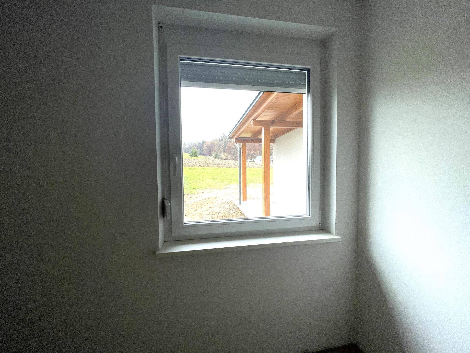 Helles Zimmer mit Fenster und Rollladen, bietet einen Ausblick auf die umliegende Landschaft.