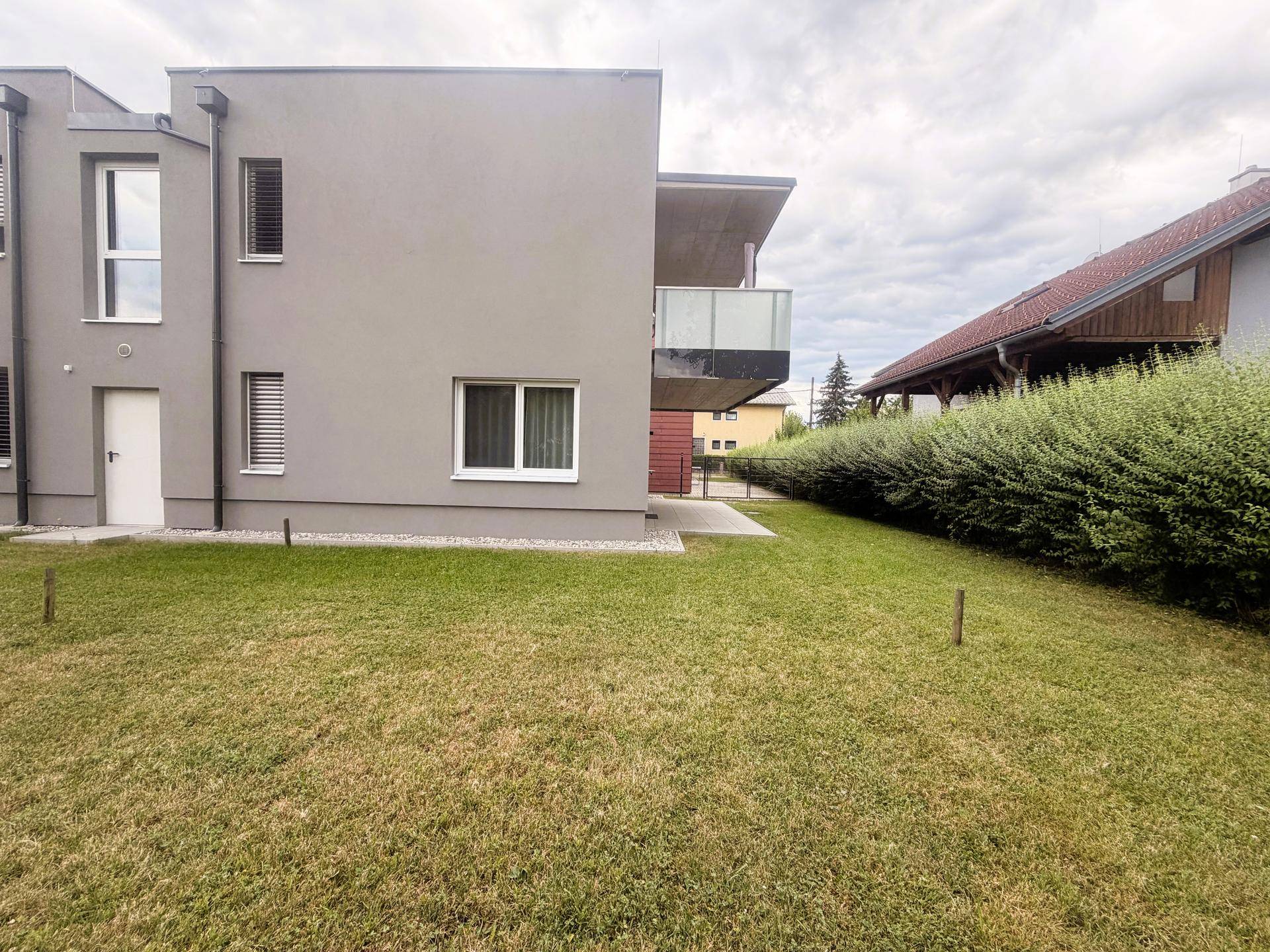 Ansicht des modernen Gebäudes von der Gartenseite mit Balkon und Fenstern.