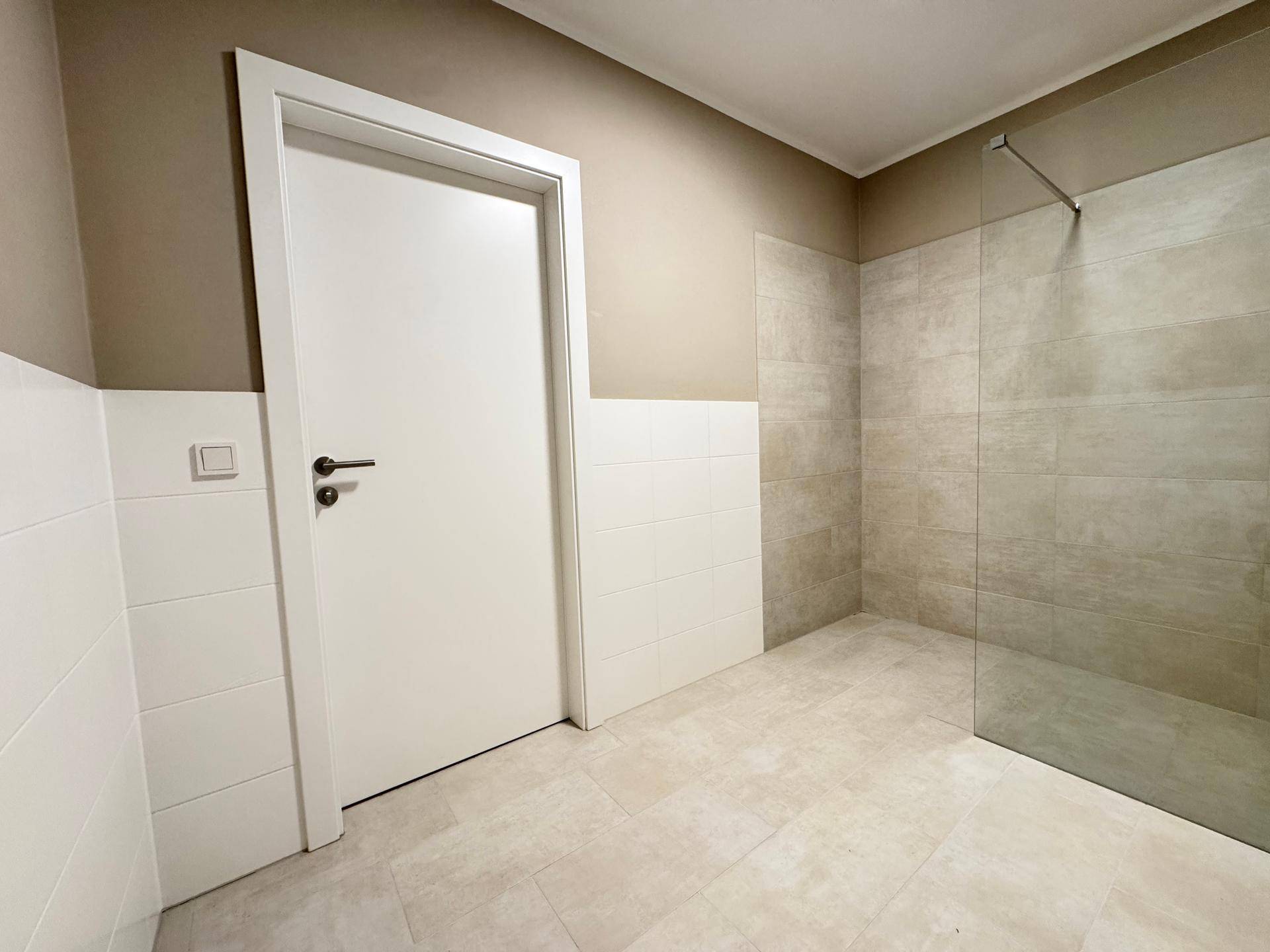 Helles Badezimmer mit großzügiger begehbarer Dusche und modernen Fliesen.