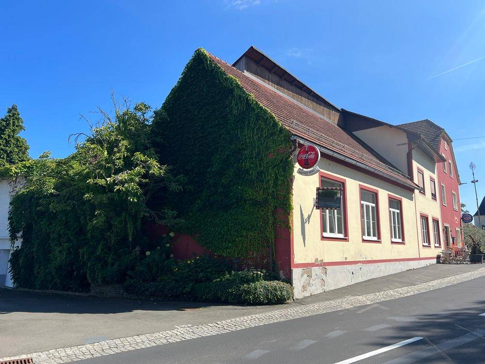 Seitenansicht des Gebäudes mit dichtem Efeu an der Wand und rotem Dach.